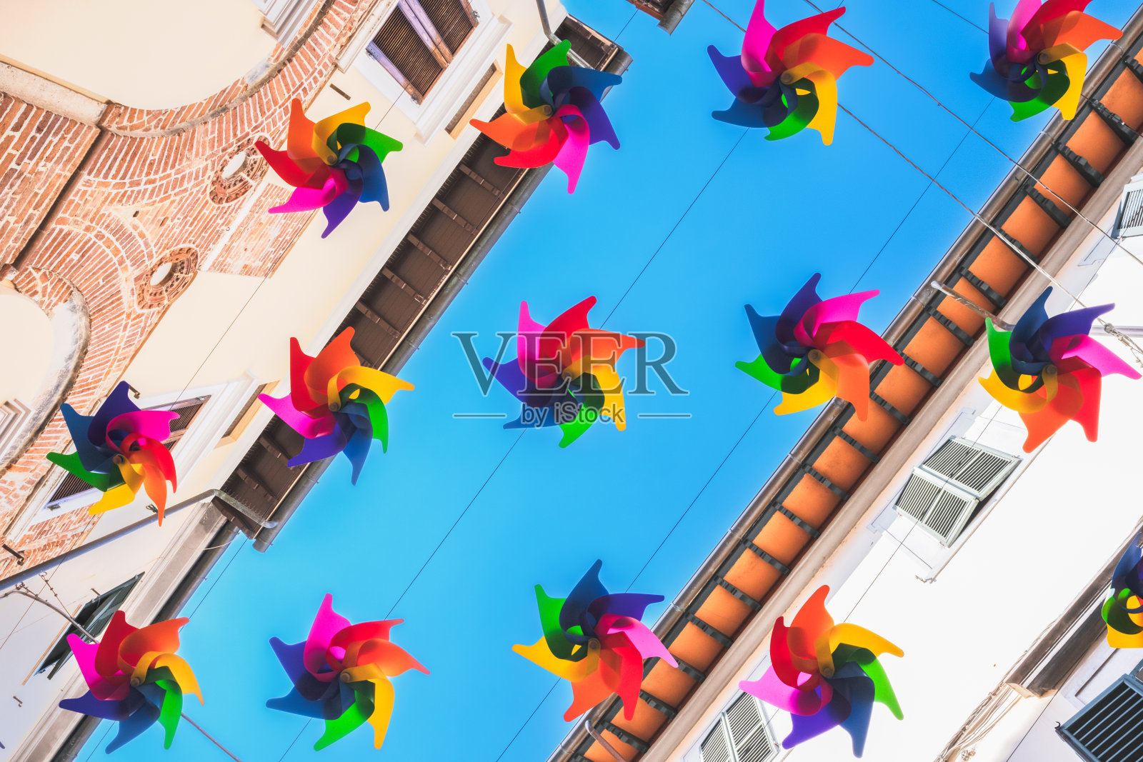 彩色彩虹扇悬挂在建筑物之间，街道装饰照片摄影图片