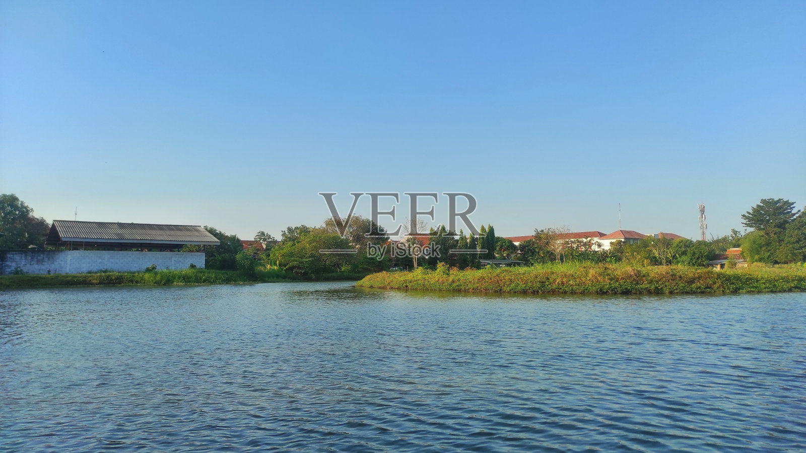 阳光明媚的日子里，城市公园湖中央的小岛照片摄影图片