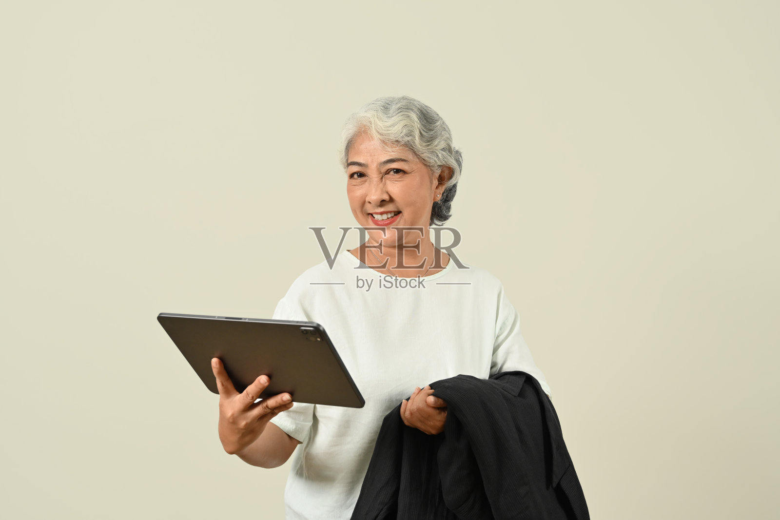 现代白发女子手持数码平板电脑，孤立地站在白色背景上。照片摄影图片