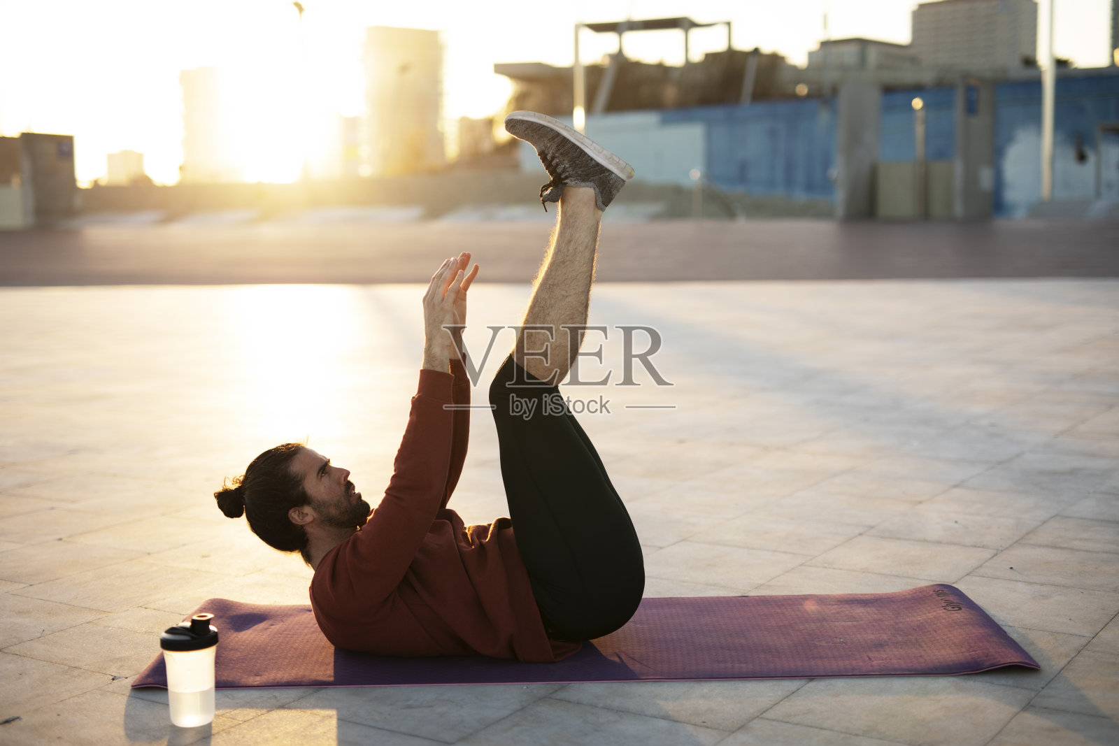 户外健身训练。帅哥在大清早做伸展运动。照片摄影图片