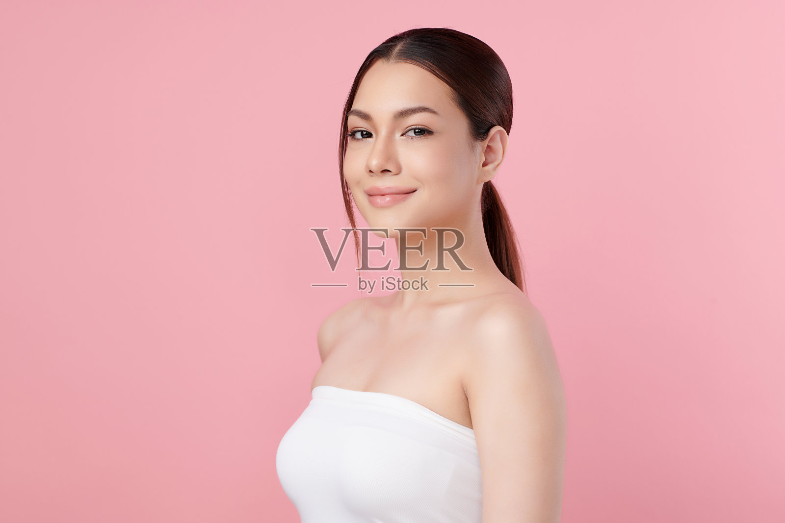 美丽的年轻亚洲女性干净新鲜的皮肤在粉红色的背景，面部护理，面部护理，美容，美容和水疗，亚洲女性肖像。照片摄影图片