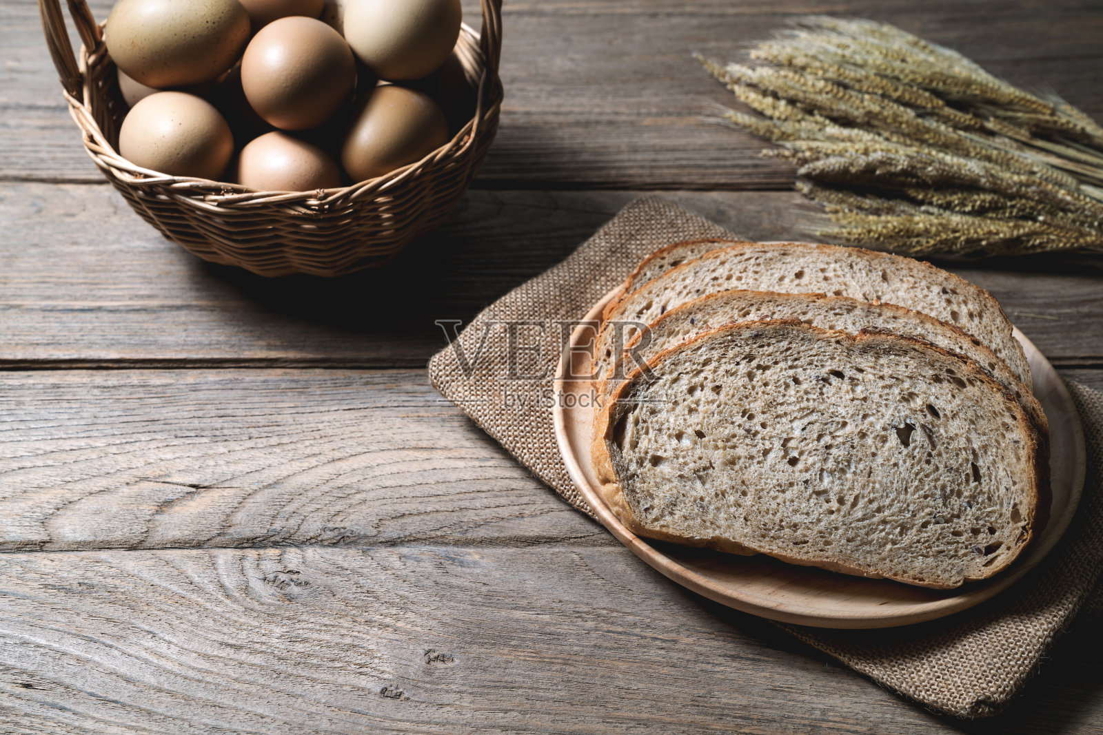 木质背景上的面包、麦穗和麻袋。照片摄影图片