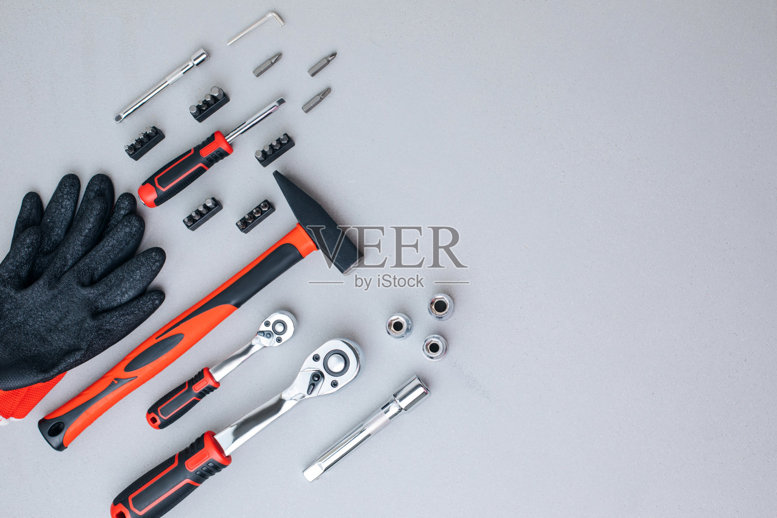 一套工作工具，一个锤子，一个螺丝刀，一个带着工作手套的灰色混凝土背景上的回答插座照片摄影图片