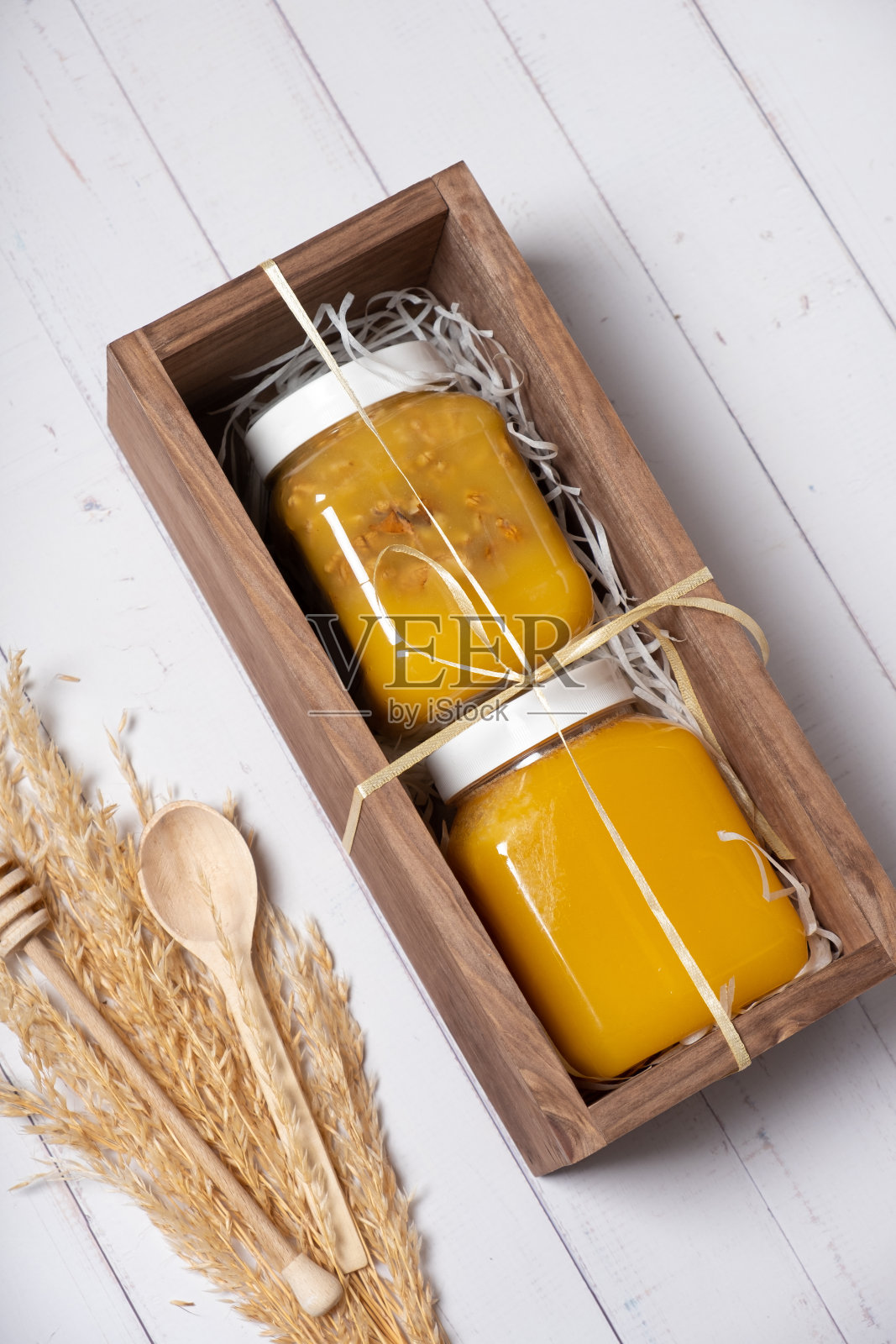 一套装有蜂蜜和坚果的罐子，蜂蜜装在木箱里，俯视图，平放照片摄影图片