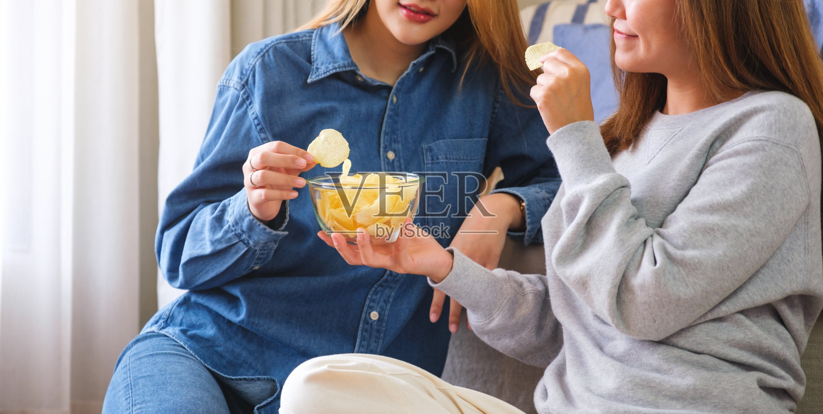 一对妇女一起分享和吃薯片的特写照片照片摄影图片