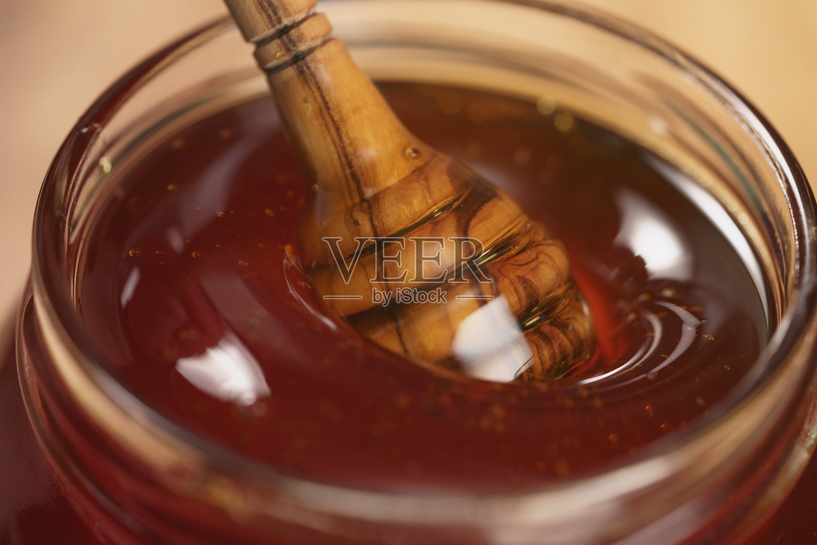 将有机蜂蜜倒入玻璃罐中照片摄影图片