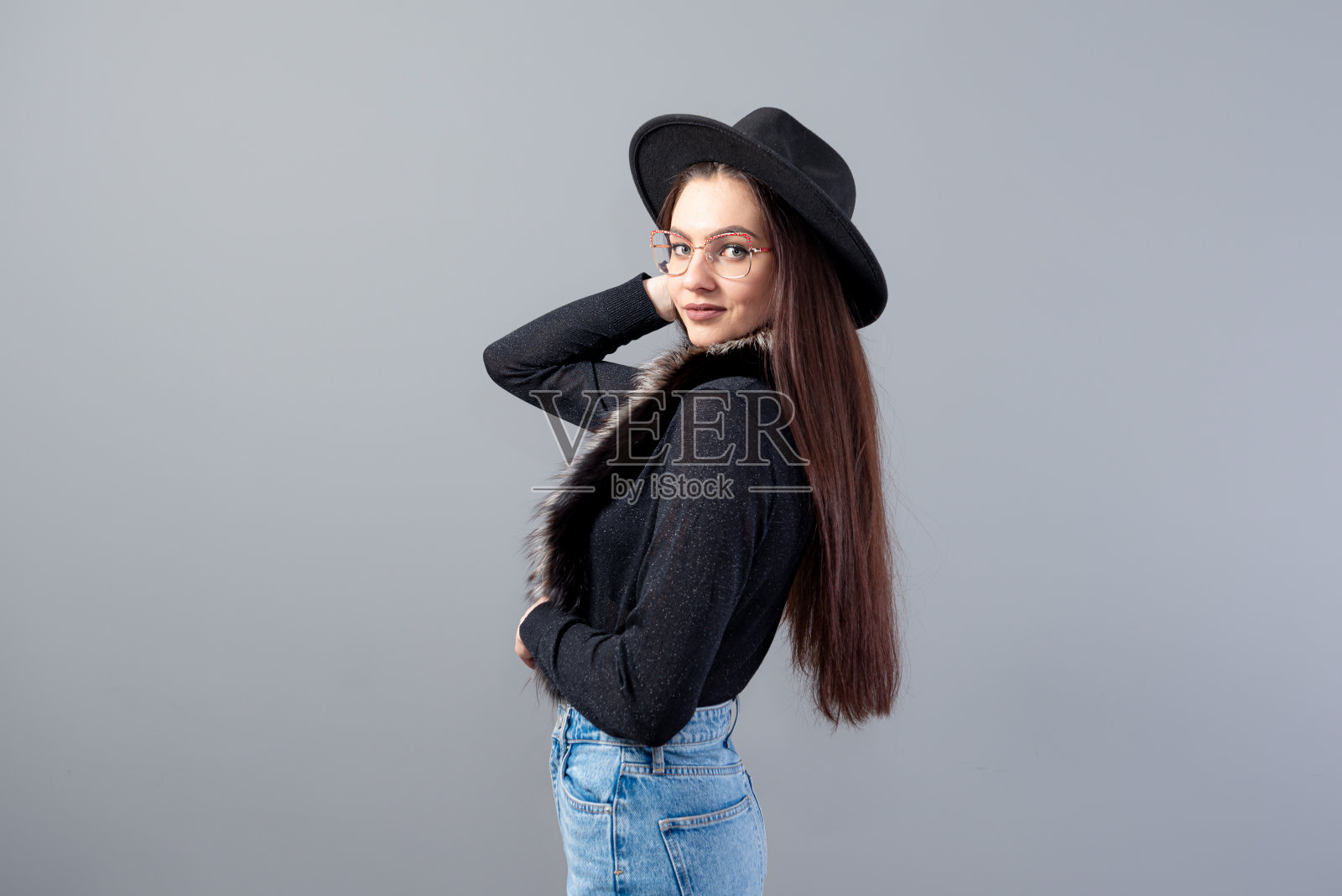 一个性感的女人的肖像，长头发，头上戴着一顶黑帽子，孤立在灰色的背景上照片摄影图片