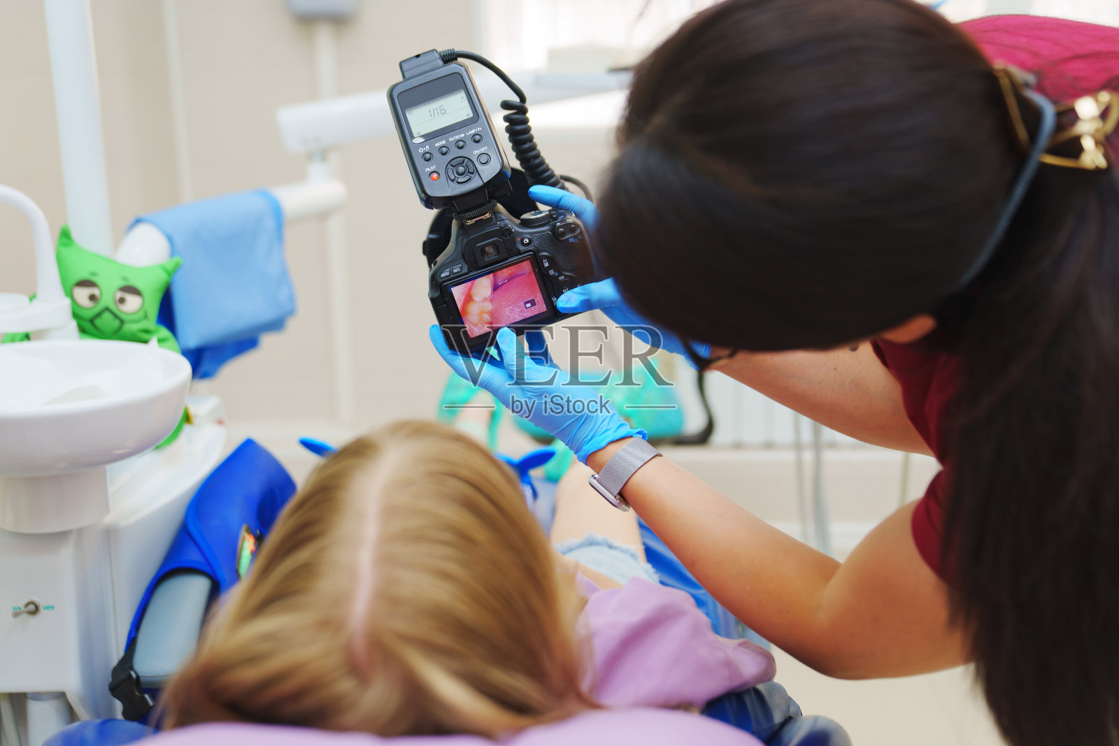 一名儿科牙医在相机屏幕上给一个小病人看牙齿的照片。照片摄影图片