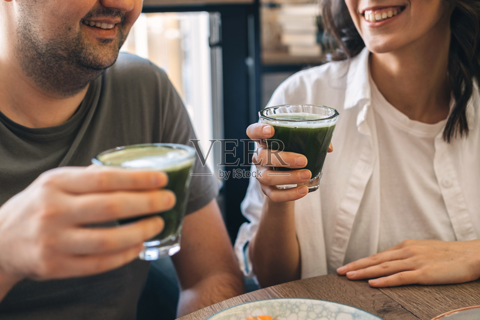 一个年轻的快乐的男人和一个女人坐在咖啡馆里喝抹茶，手近距离。健康饮食理念照片摄影图片