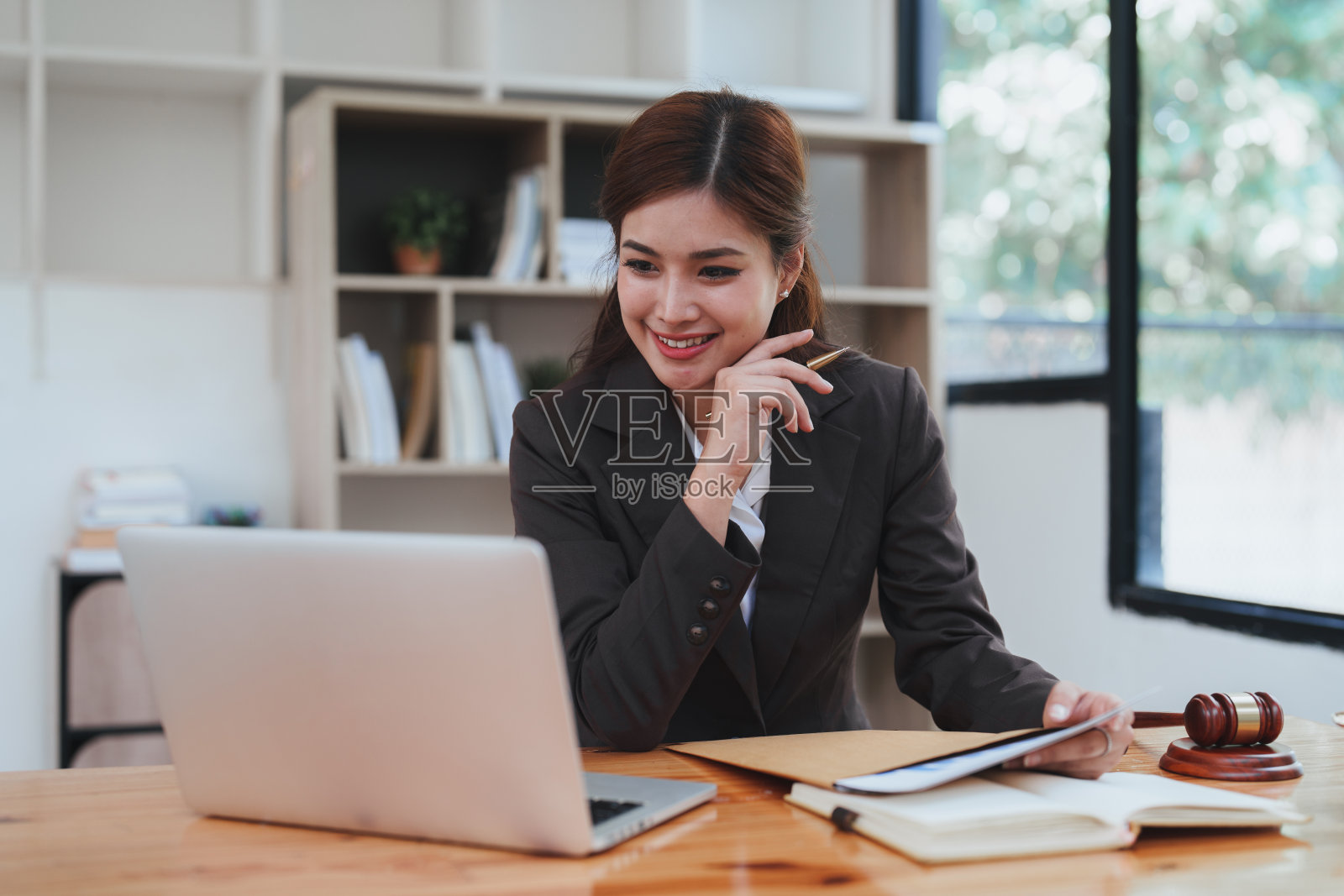 年轻的律师在办公室，女商人和律师在办公室的木桌上用黄铜秤讨论合同文件。法律，法律服务，咨询，司法和房地产的概念照片摄影图片