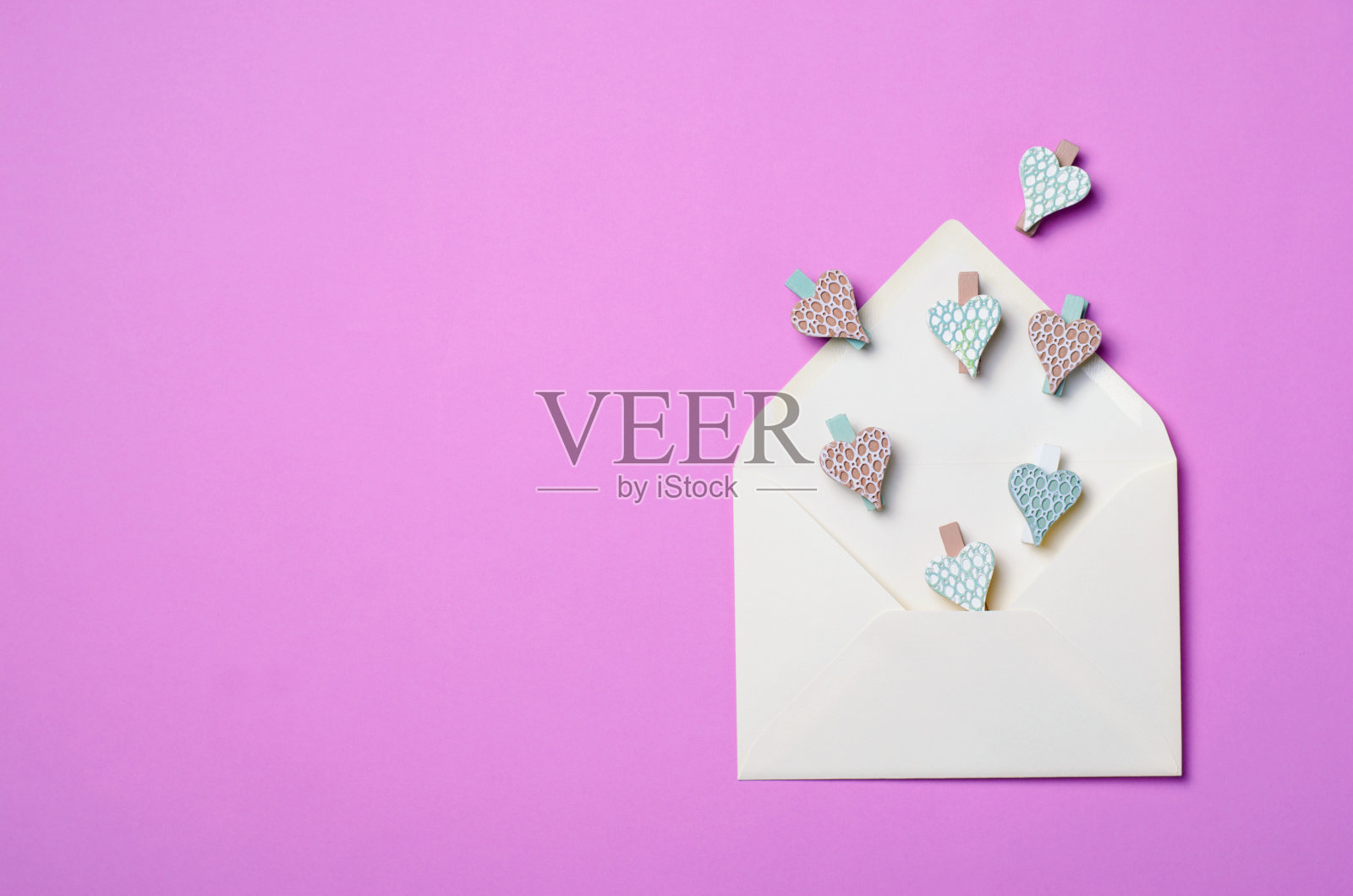 白色信封上的紫色背景和心形别针，俯视图照片摄影图片