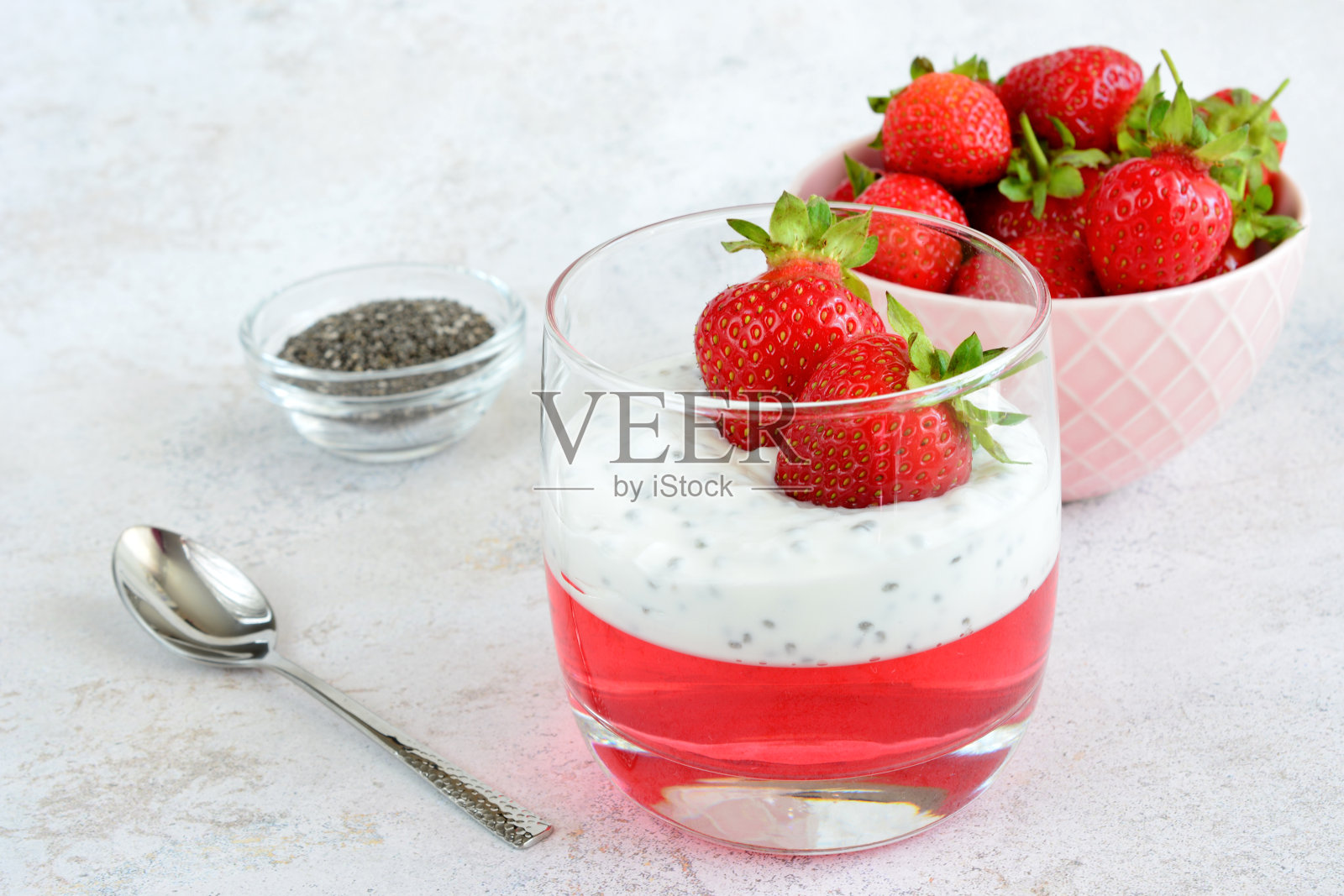 草莓甜点与果冻和奇亚籽在饮用杯与草莓碗和勺子照片摄影图片
