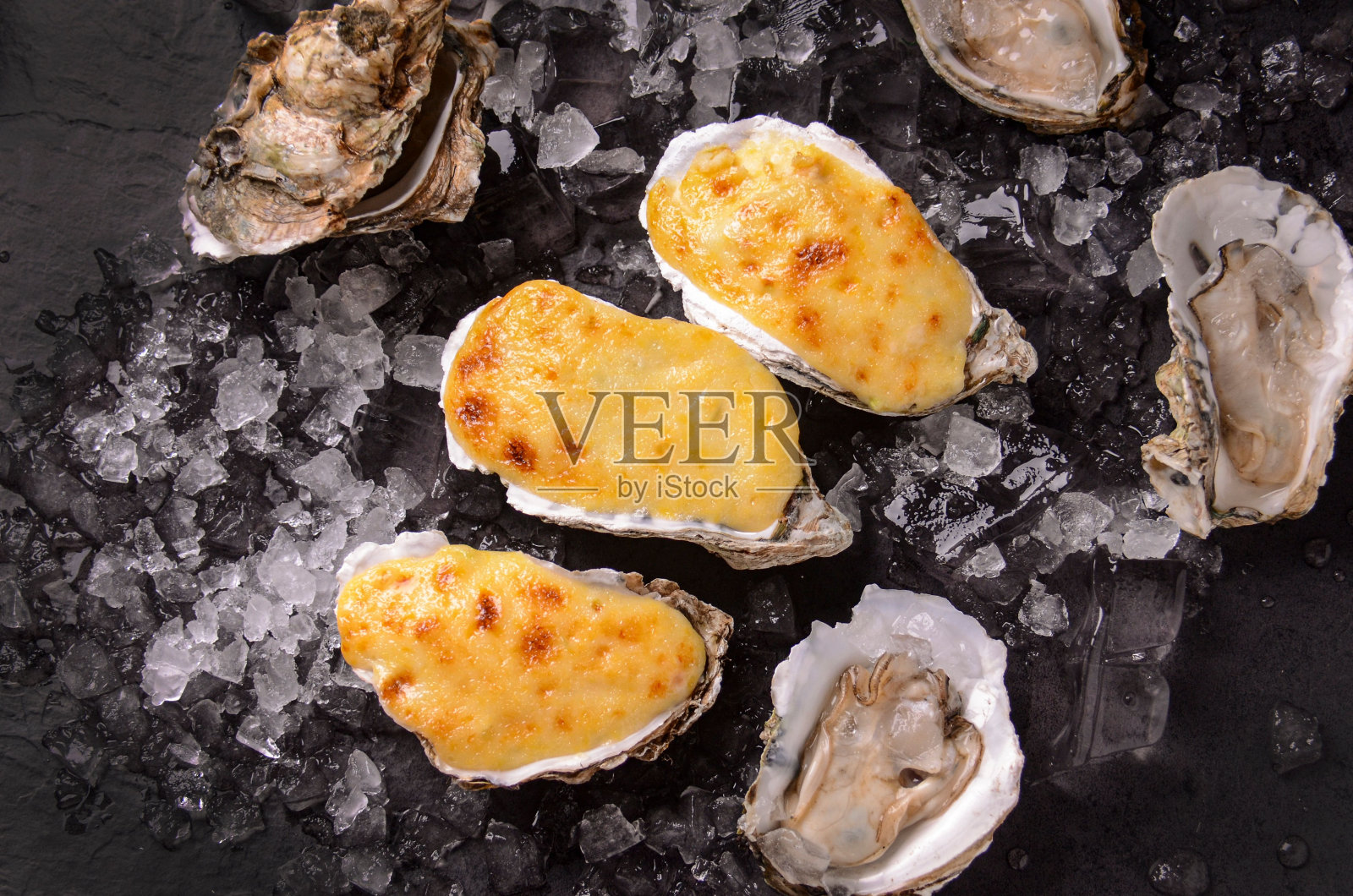 一盘新鲜烤牡蛎的特写，上面有奶油奶酪照片摄影图片