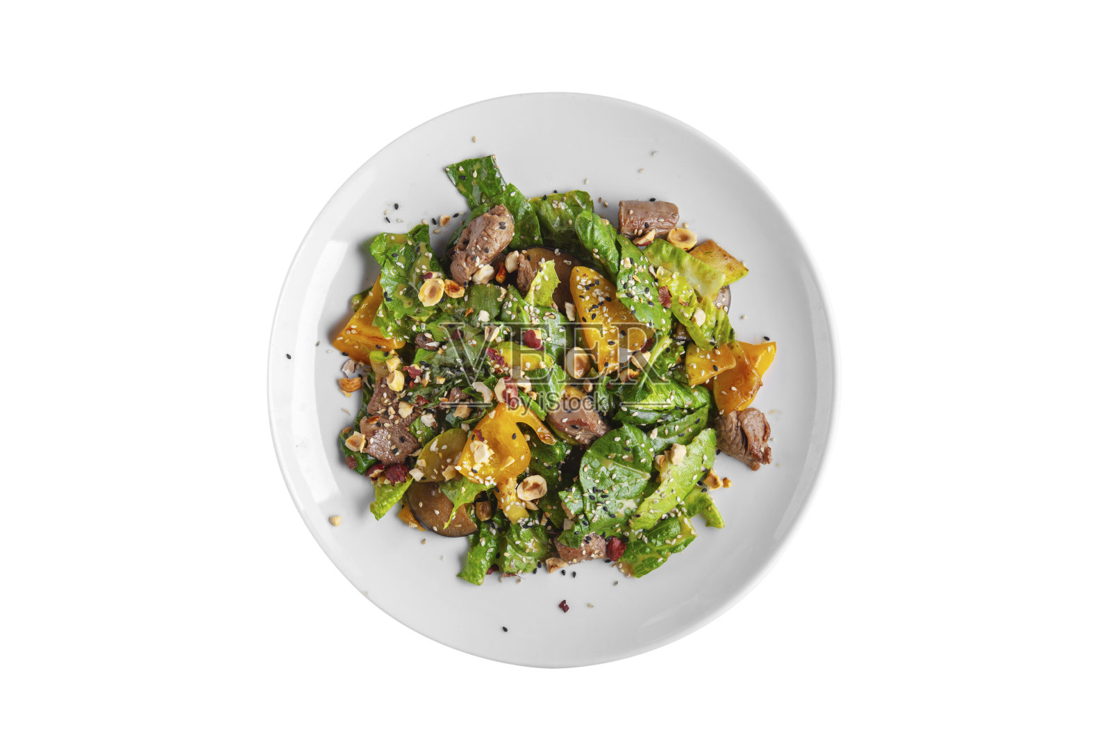 沙拉里有肉、胡椒、芝麻菜、酱汁、榛子、芝麻、菠菜和西葫芦放在白色盘子里照片摄影图片