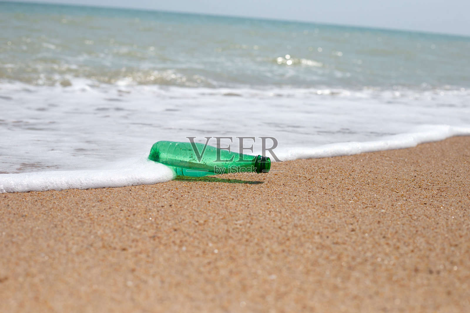 海滩上的绿色塑料瓶照片摄影图片