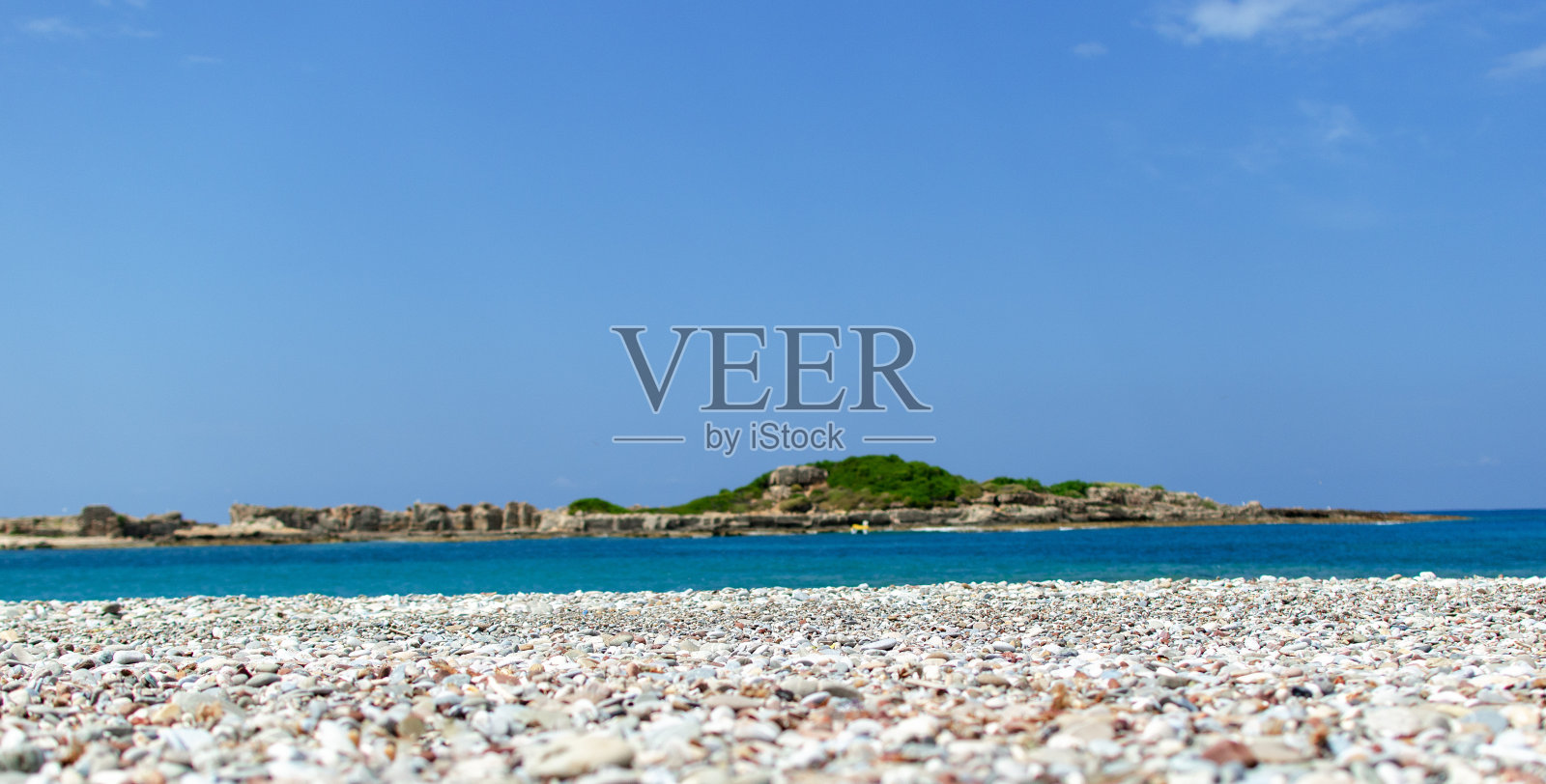 海边有石头，天空蔚蓝。照片摄影图片