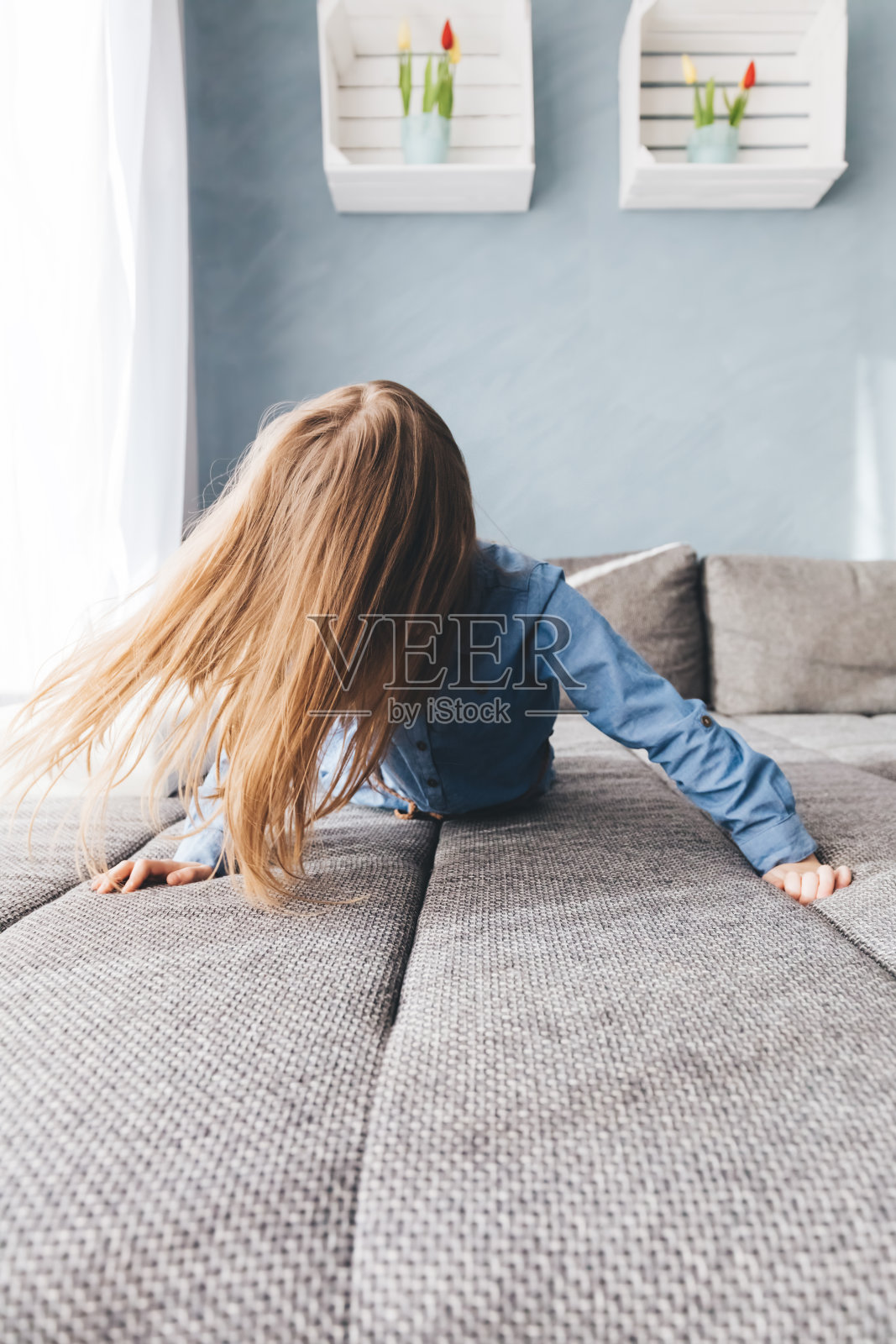 快乐的小女孩在家里的沙发上玩耍。照片摄影图片