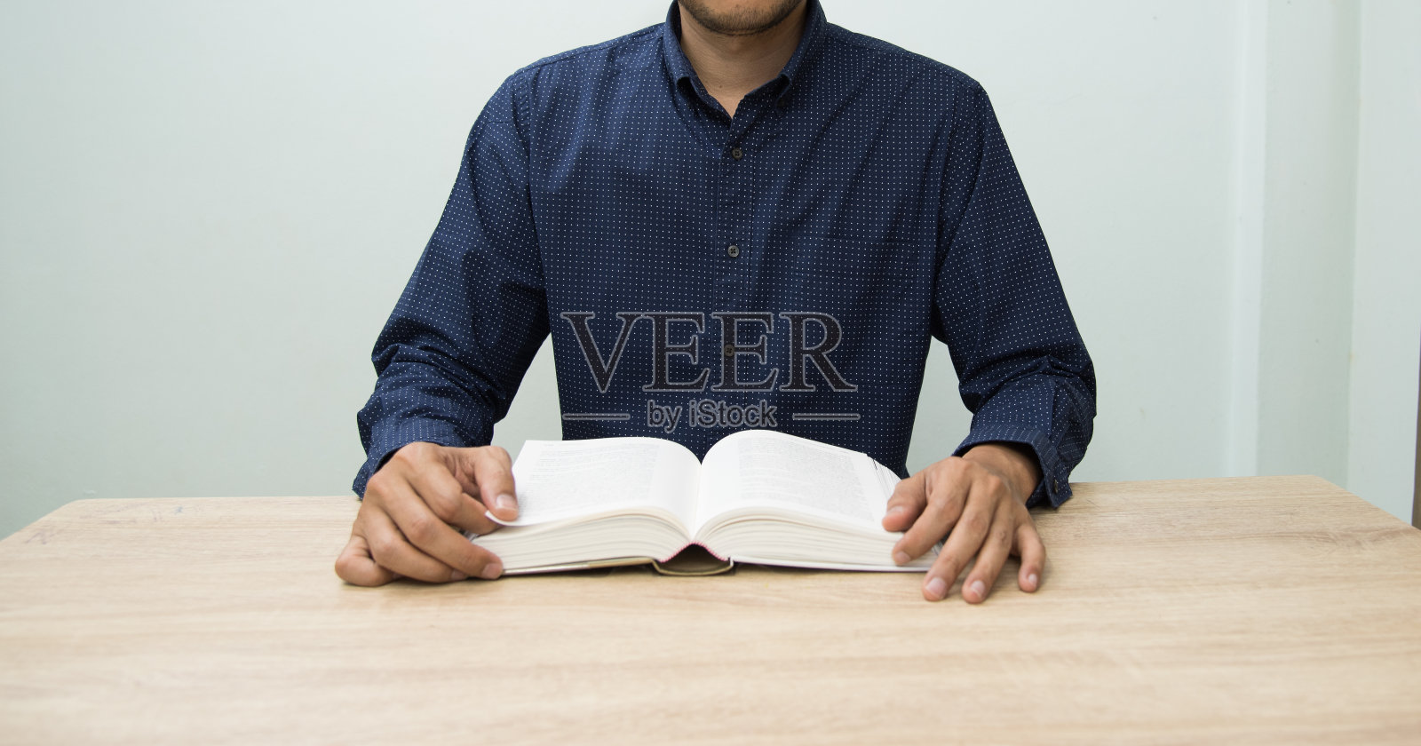 穿深蓝色衬衫的男人在大学图书馆看书。照片摄影图片