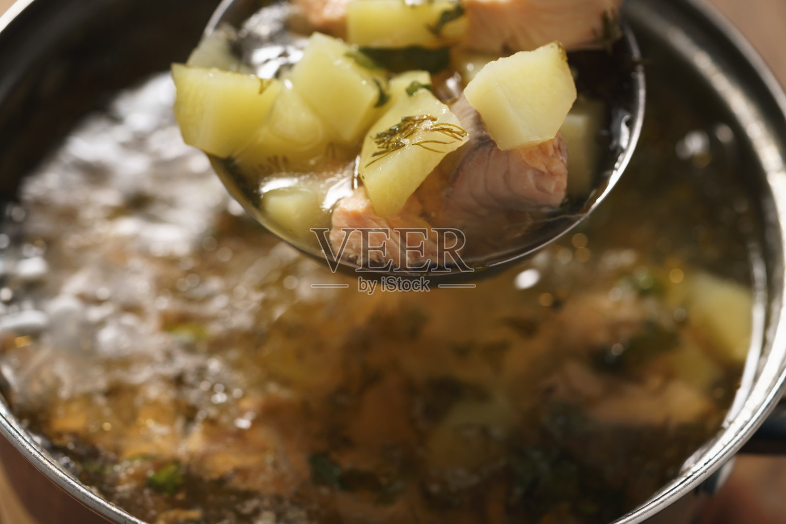 在锅里准备了热鳟鱼汤和土豆照片摄影图片