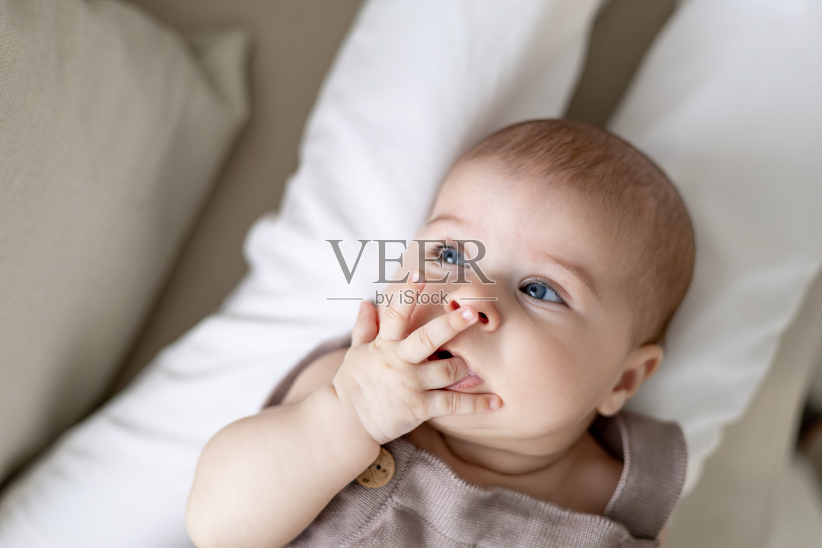 一个六个月大的女婴躺在妈妈的怀里吮吸着手指，一个可爱的小女孩的肖像照片摄影图片