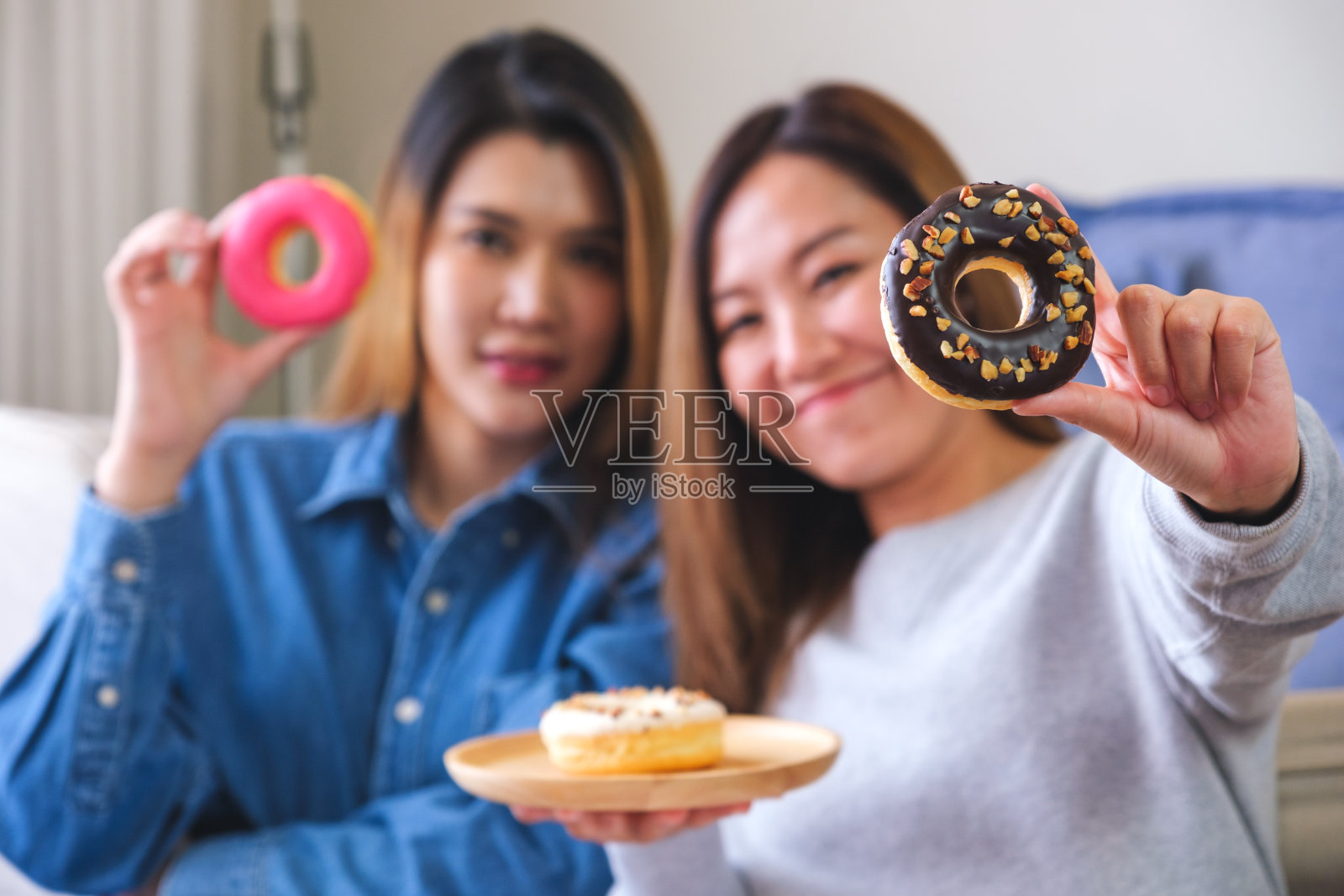 一张模糊的照片，闺蜜两人，女人一起拿着一块甜甜圈照片摄影图片