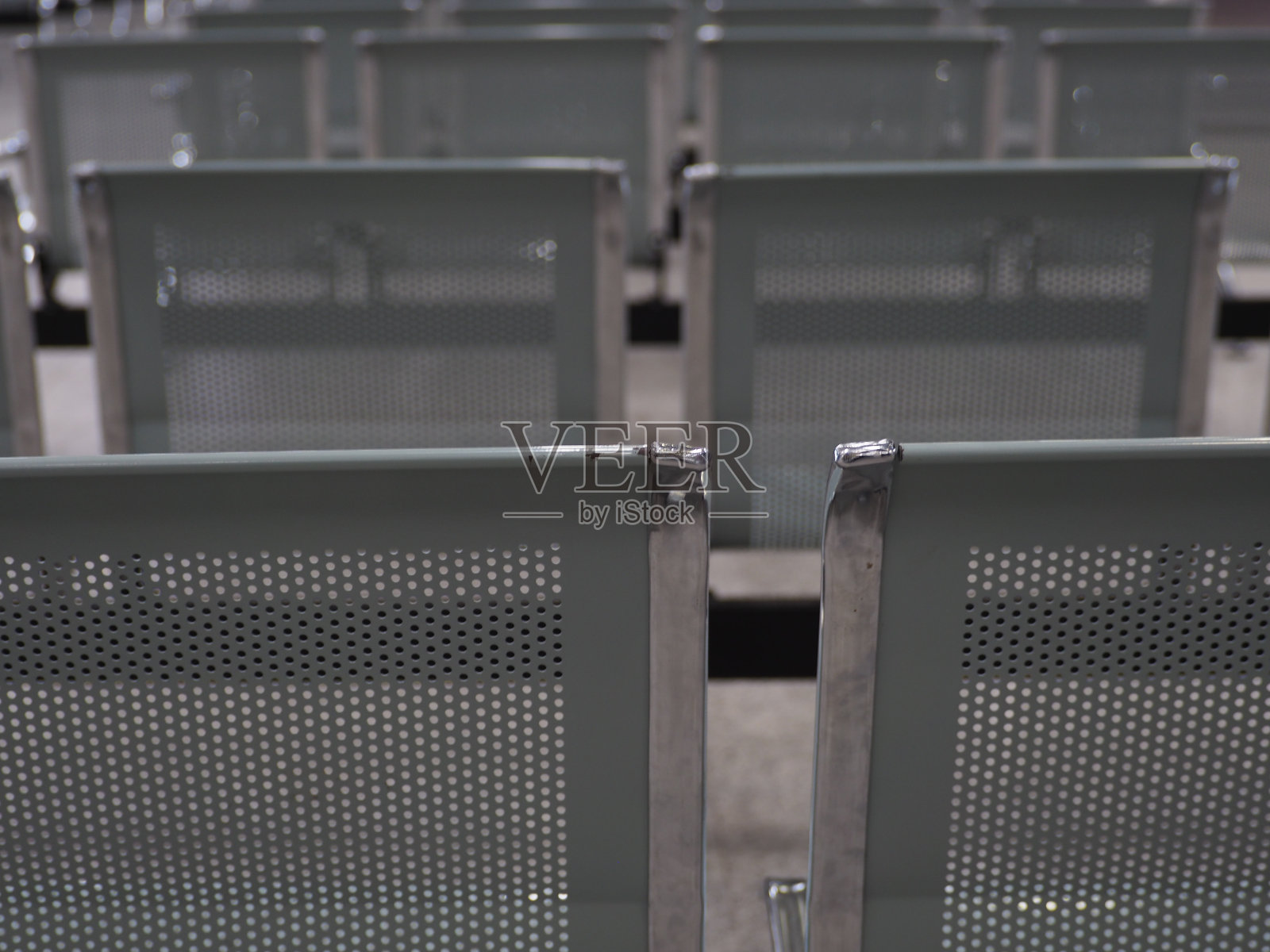 铁椅子，黄白色的灯光，灰黑色的天花板。照片摄影图片