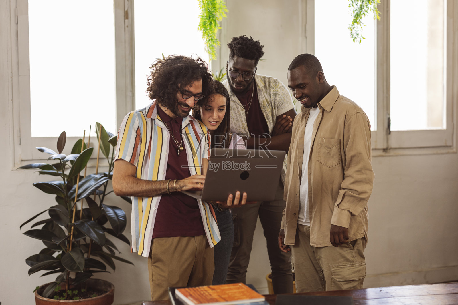 不同种族的同事们围坐在笔记本电脑前，全神贯注地投入到项目的复杂性中，他们将专业知识和创造力结合起来，共同努力，将愿景变为现实。照片摄影图片