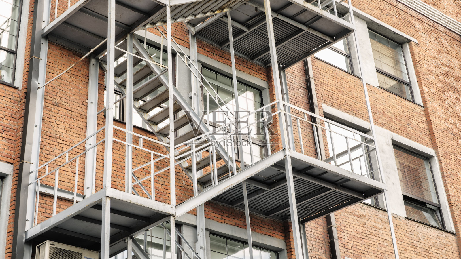 红砖经典建筑外墙的消防梯，旧工业建筑红砖与金属雨水管照片摄影图片