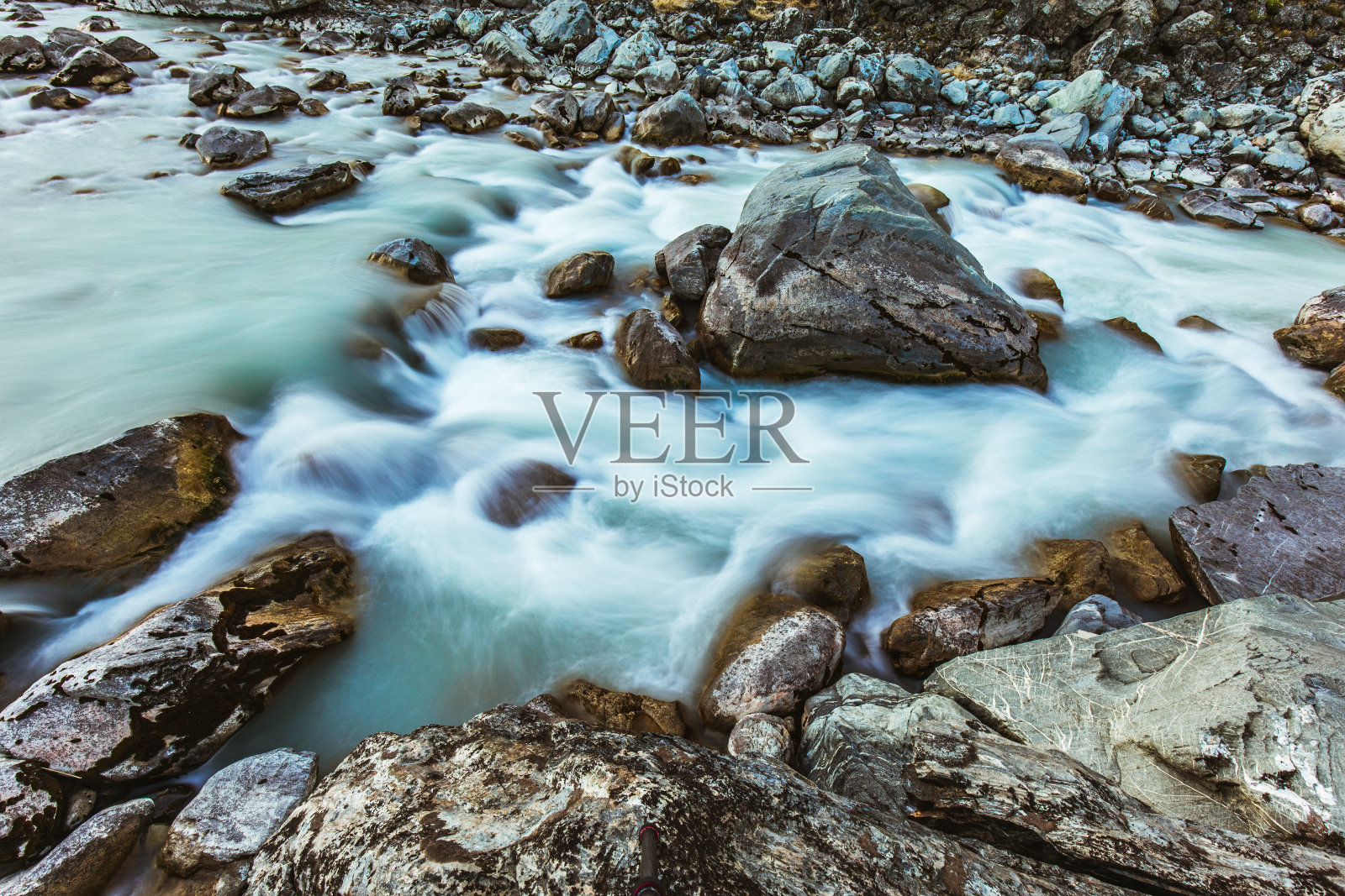 流动的水在岩石在冰川融化的河流在新西兰的山区照片摄影图片