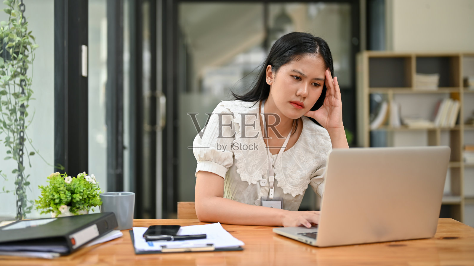 紧张的亚洲女商人担心她的项目，在她的笔记本电脑上工作。照片摄影图片