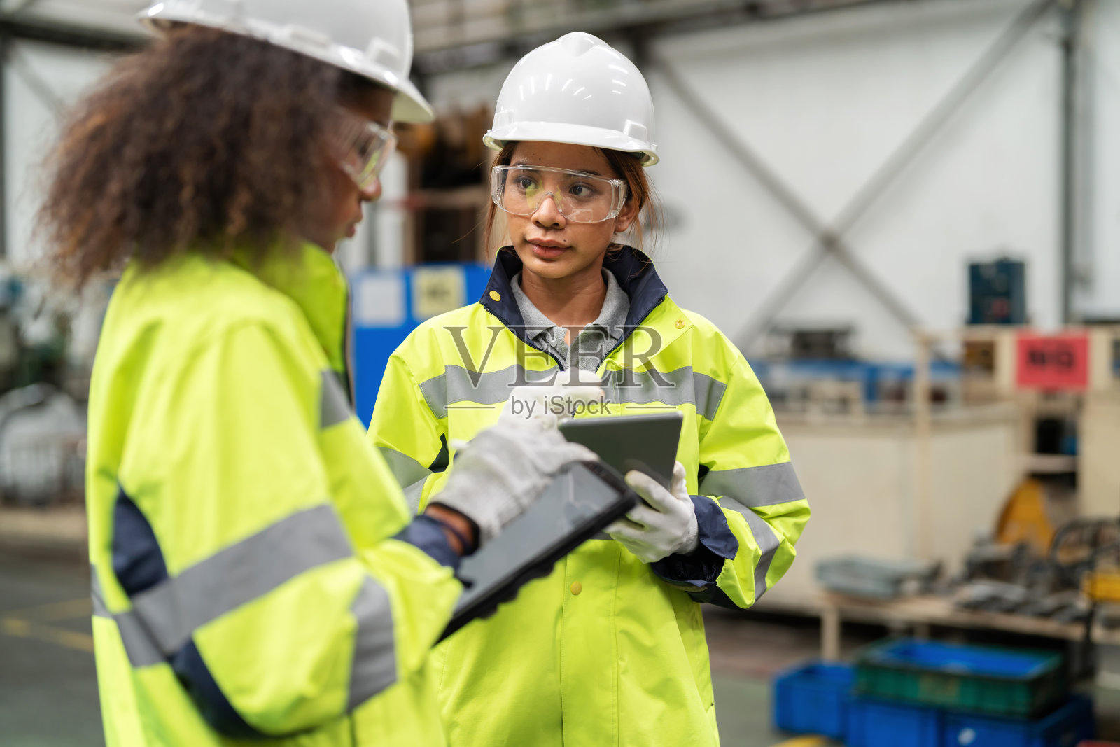 生产过程的优化有助于提高生产率。生产工程师女在工厂与主管站在一起，使用数码平板电脑跟踪部分机器故障，并在生产线的货架上检查。照片摄影图片
