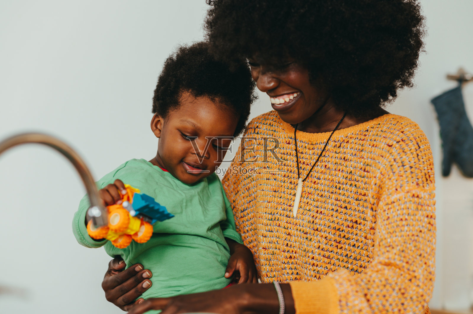一位开朗的多种族母亲和蹒跚学步的孩子在家里一起玩耍。照片摄影图片