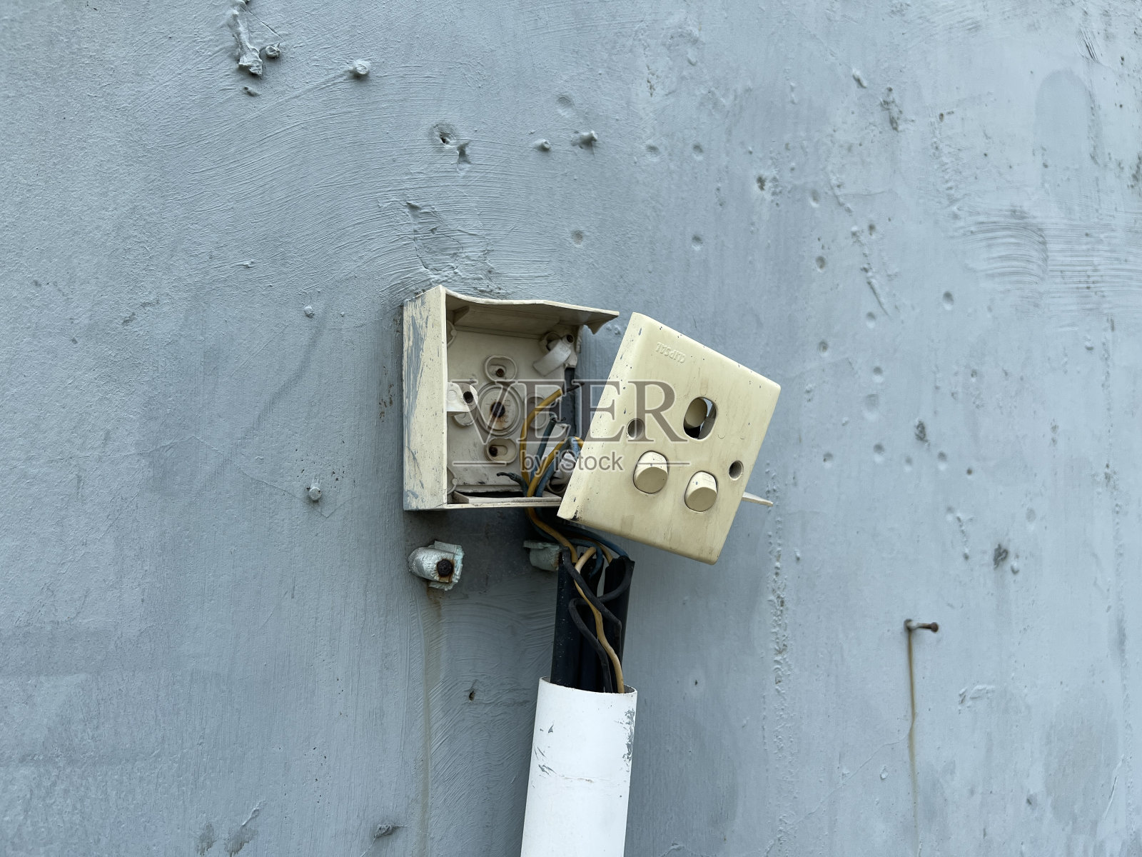 白色破损的电源开关或插座或插头或电缆在灰色墙壁上照片摄影图片