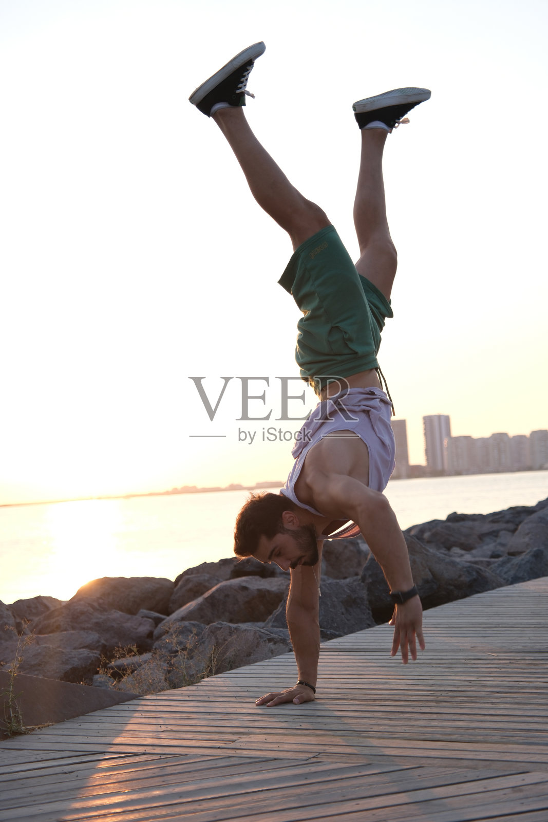 年轻的男运动员在海边做倒立照片摄影图片