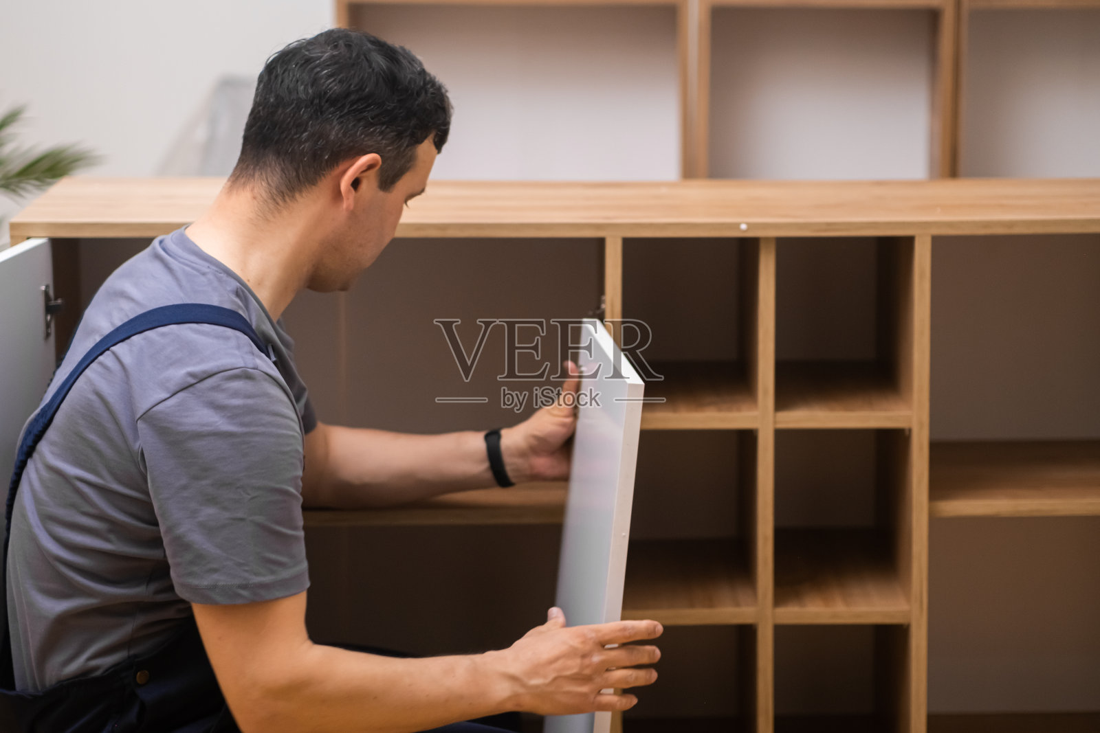 定制家具安装过程中，穿着工作服的木匠检查木柜的连接门照片摄影图片