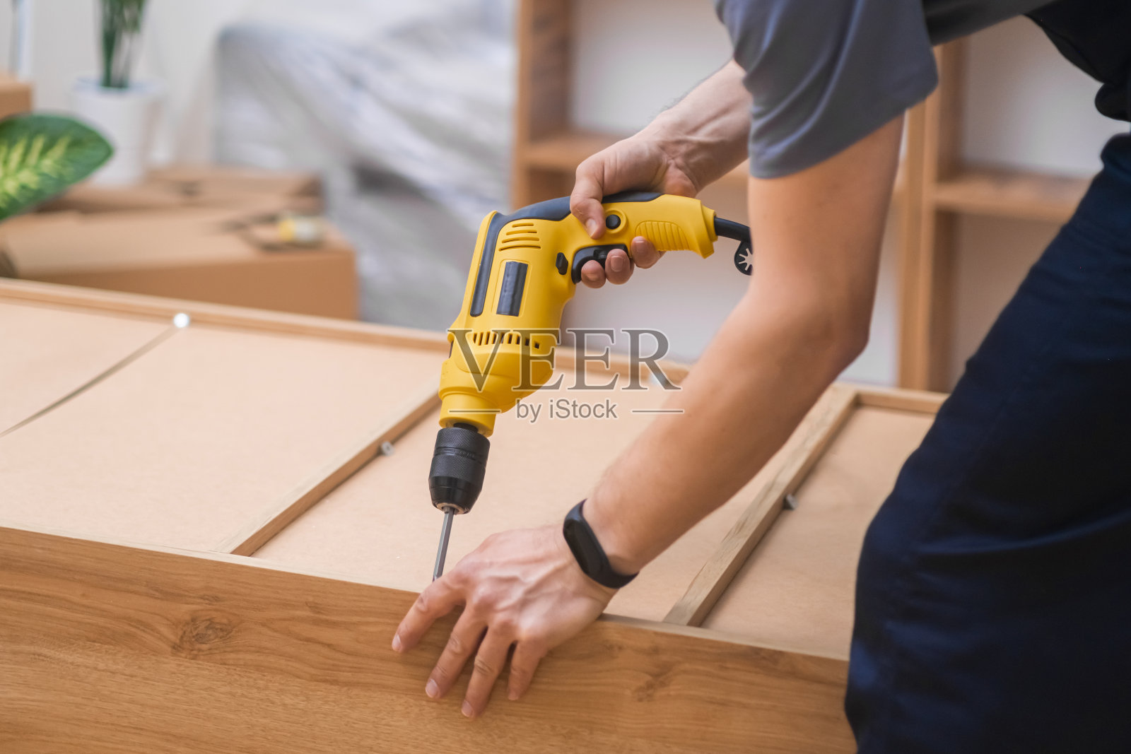 家具采用优质木质材料组装工艺，木匠使用电动螺丝刀照片摄影图片