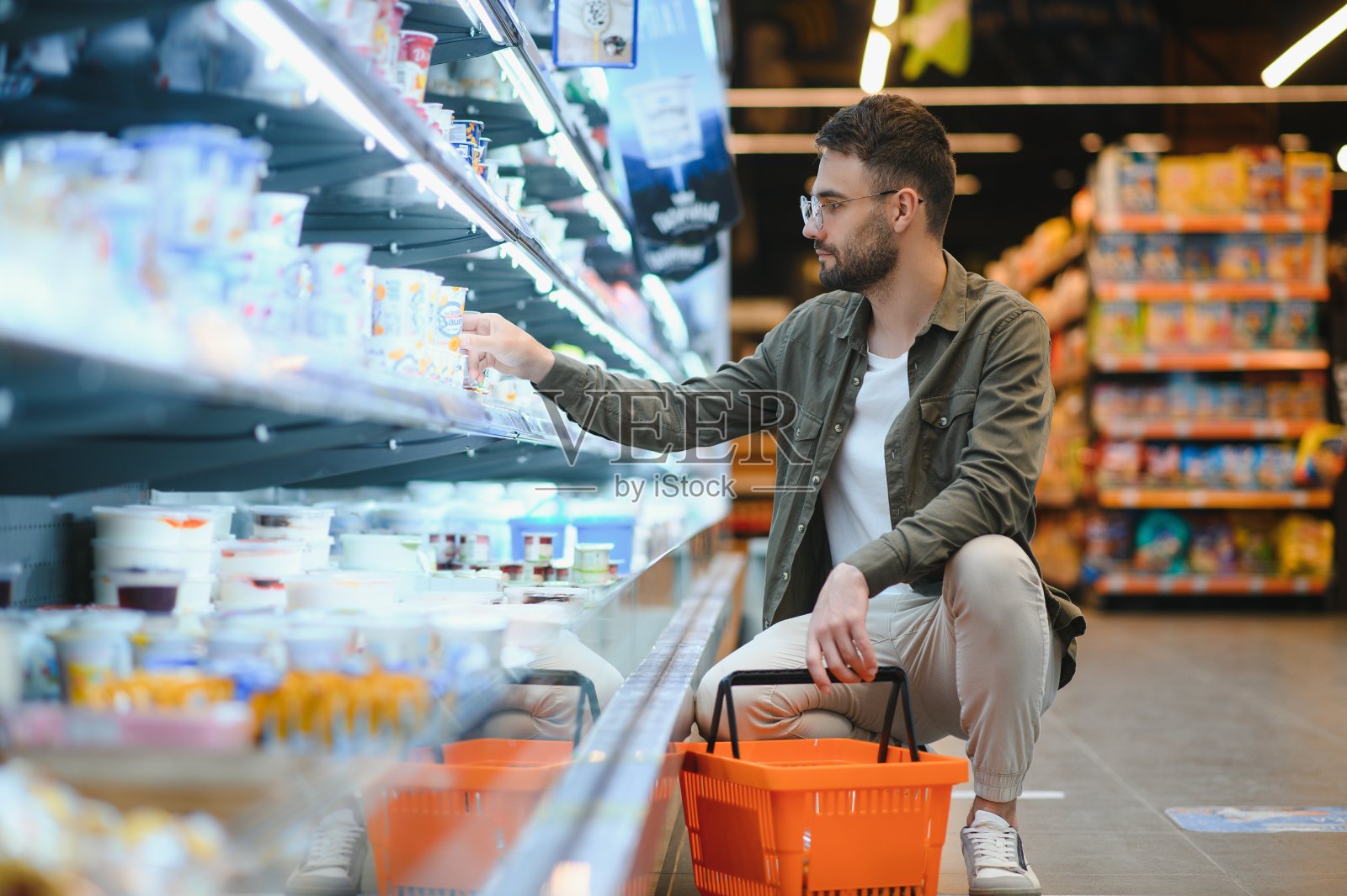 一个面带微笑的帅哥在超市购物，从货架上挑选食品照片摄影图片