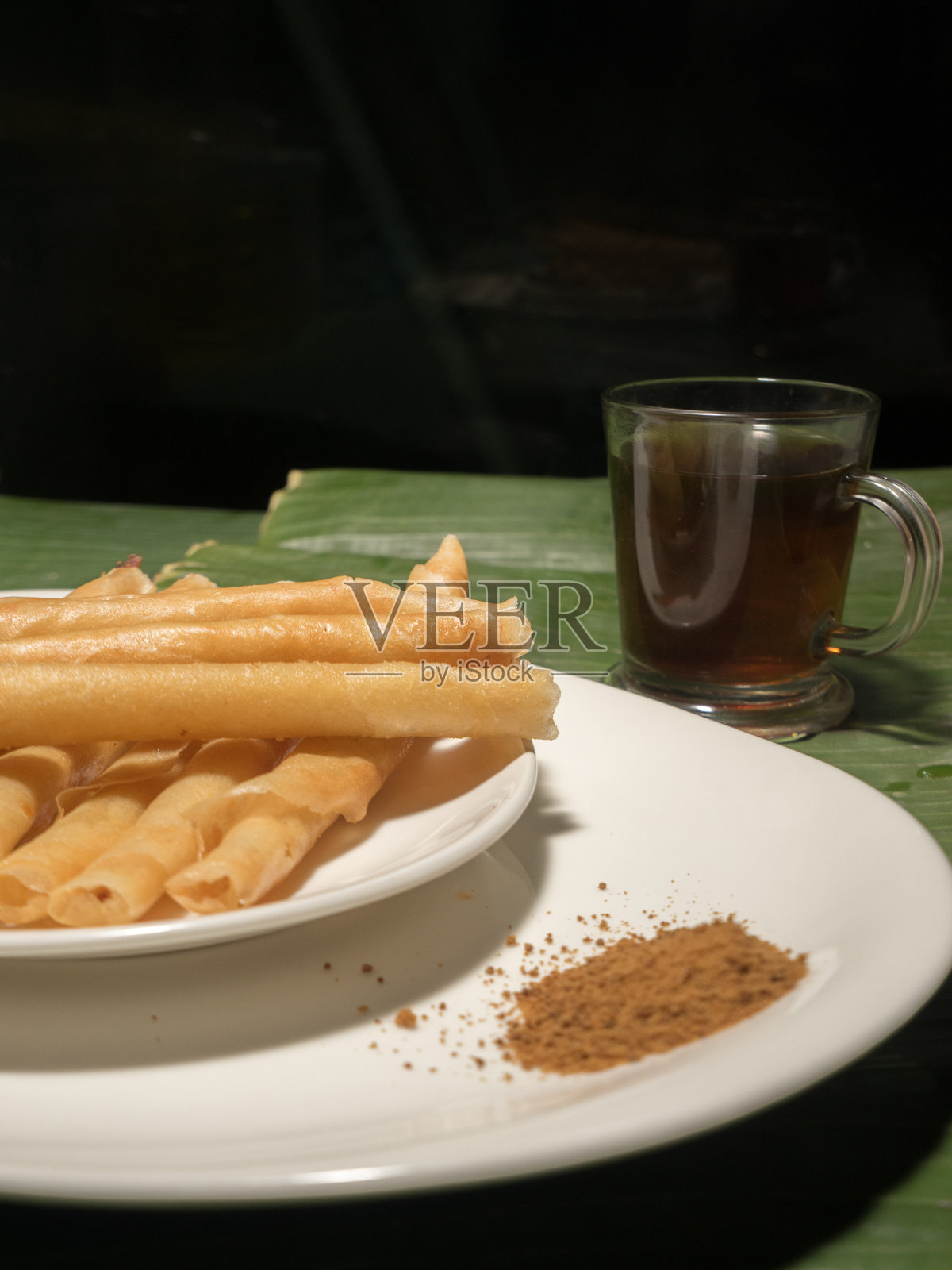 春蛋香蕉卷放在白色的盘子里，上面是香蕉叶，还有茶和棕榈糖照片摄影图片