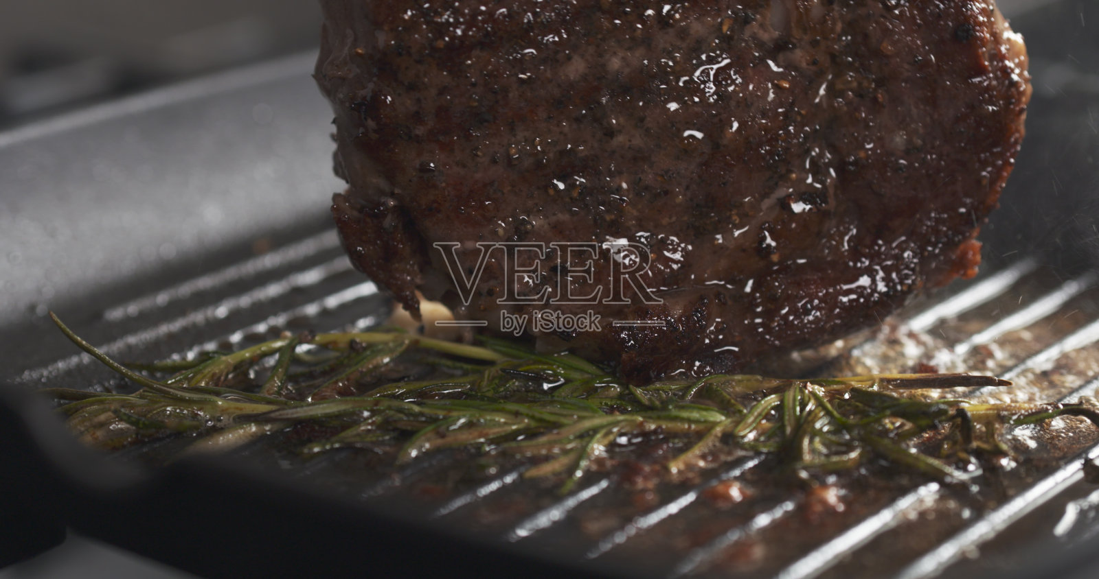 在烤盘上用香草烹饪肋眼牛排照片摄影图片