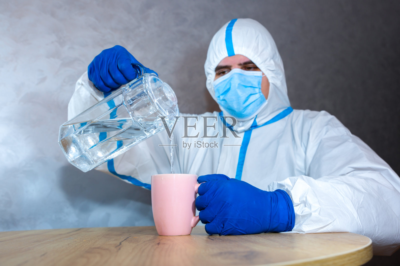 身穿医疗防护服、戴口罩、戴手套的医生正在为检测倒水。病毒流行保护mers。冠状病毒(COVID-19)。医疗保健的概念。照片摄影图片