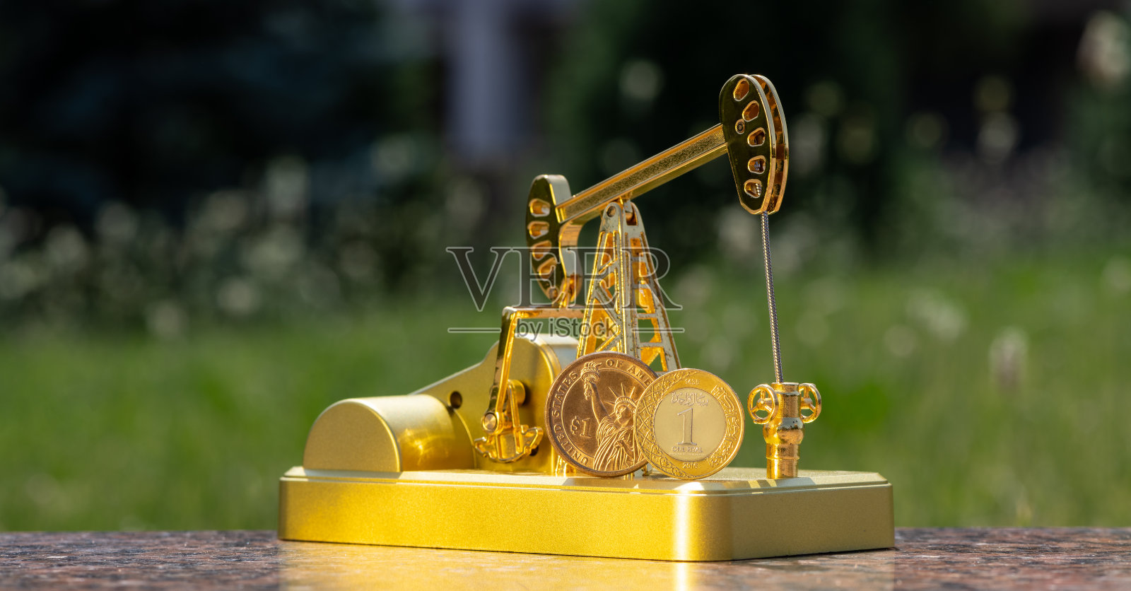 沙特阿拉伯王国1里亚尔硬币和金油泵模型上的1美元照片摄影图片