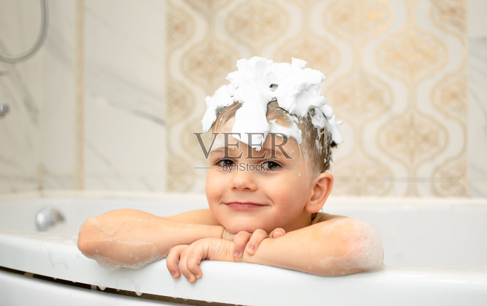 头发上有肥皂泡沫的可爱孩子在洗澡。微笑的儿童肖像特写，照顾儿童的健康和卫生。婴儿洗发水。快乐童年，卫生护肤程序。照片摄影图片