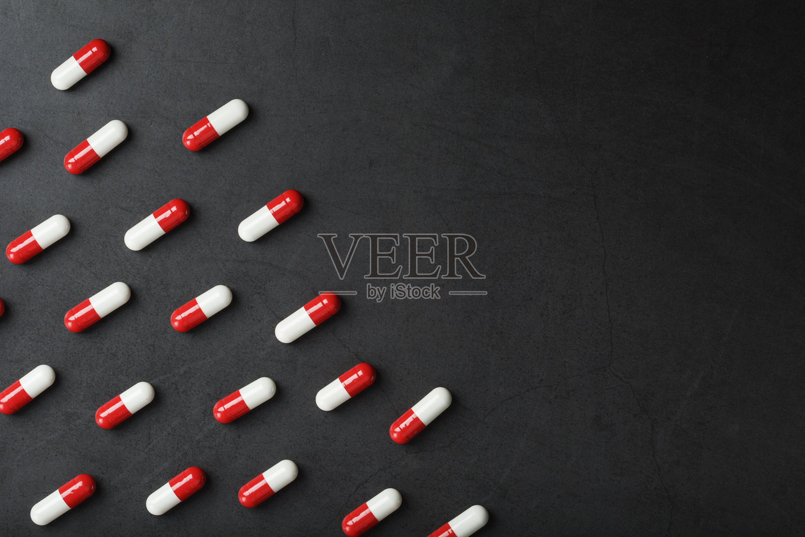 黑色背景上的红白相间的胶囊图案。照片摄影图片