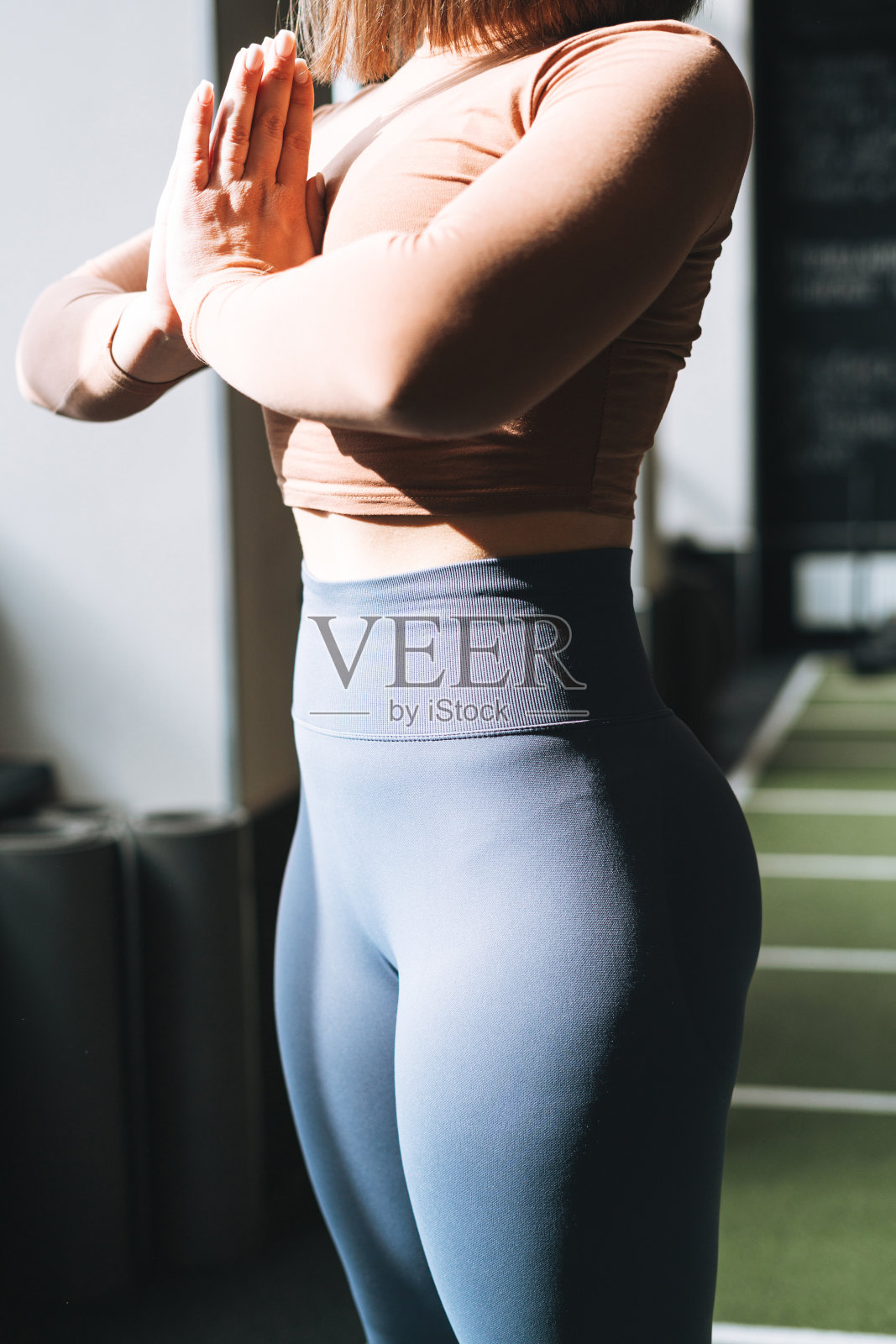 年轻的黑发女子做普拉提拉伸，在健身俱乐部的垫子上练习瑜伽照片摄影图片