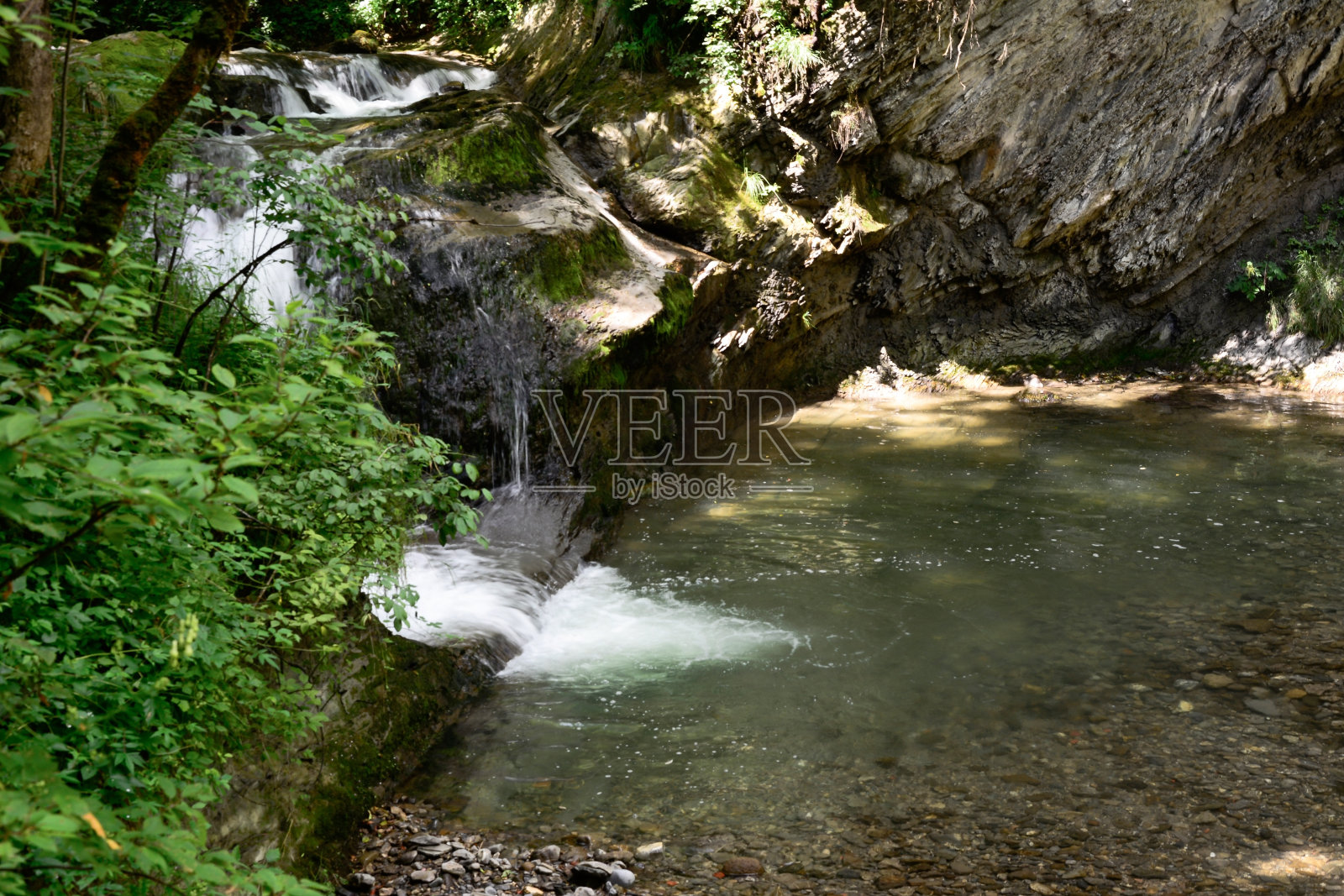 公园里岩石附近的一条小河瀑布。周围环境的自然背景照片摄影图片