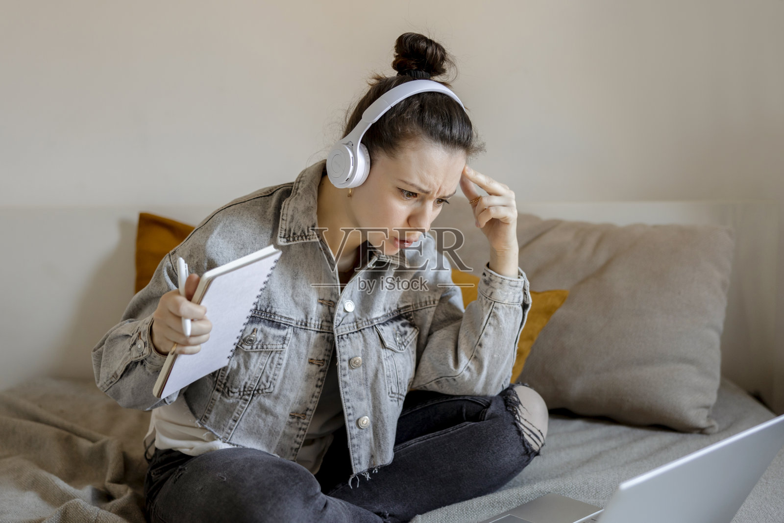 愤怒和不满的女人穿着休闲的衣服坐在家里的床上，对着电脑学习。女孩又伤心又累。负面情绪，压力，精神问题，最后期限。远程教育。照片摄影图片
