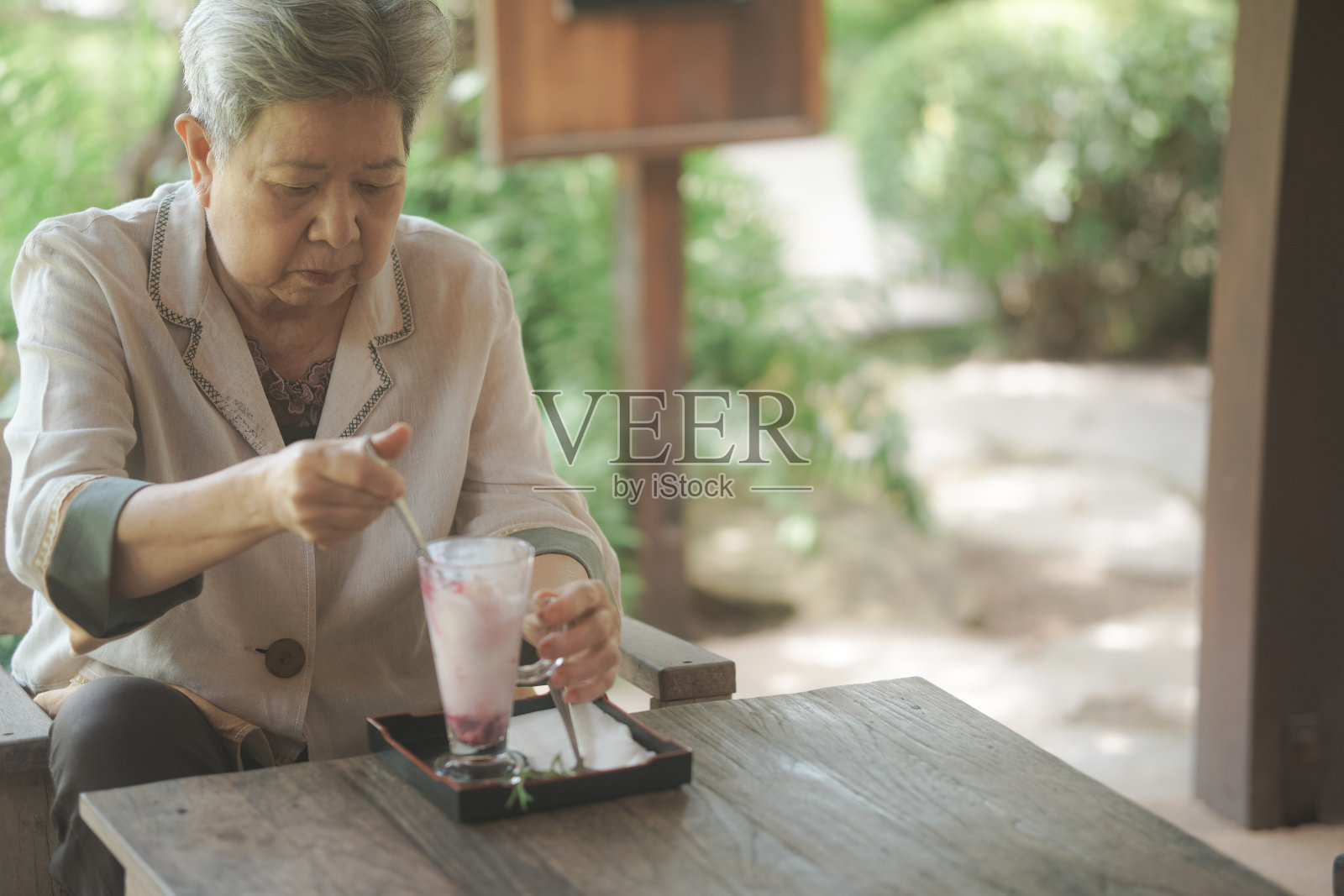 在阳台上吃冰淇淋的老妇人。退休的生活照片摄影图片