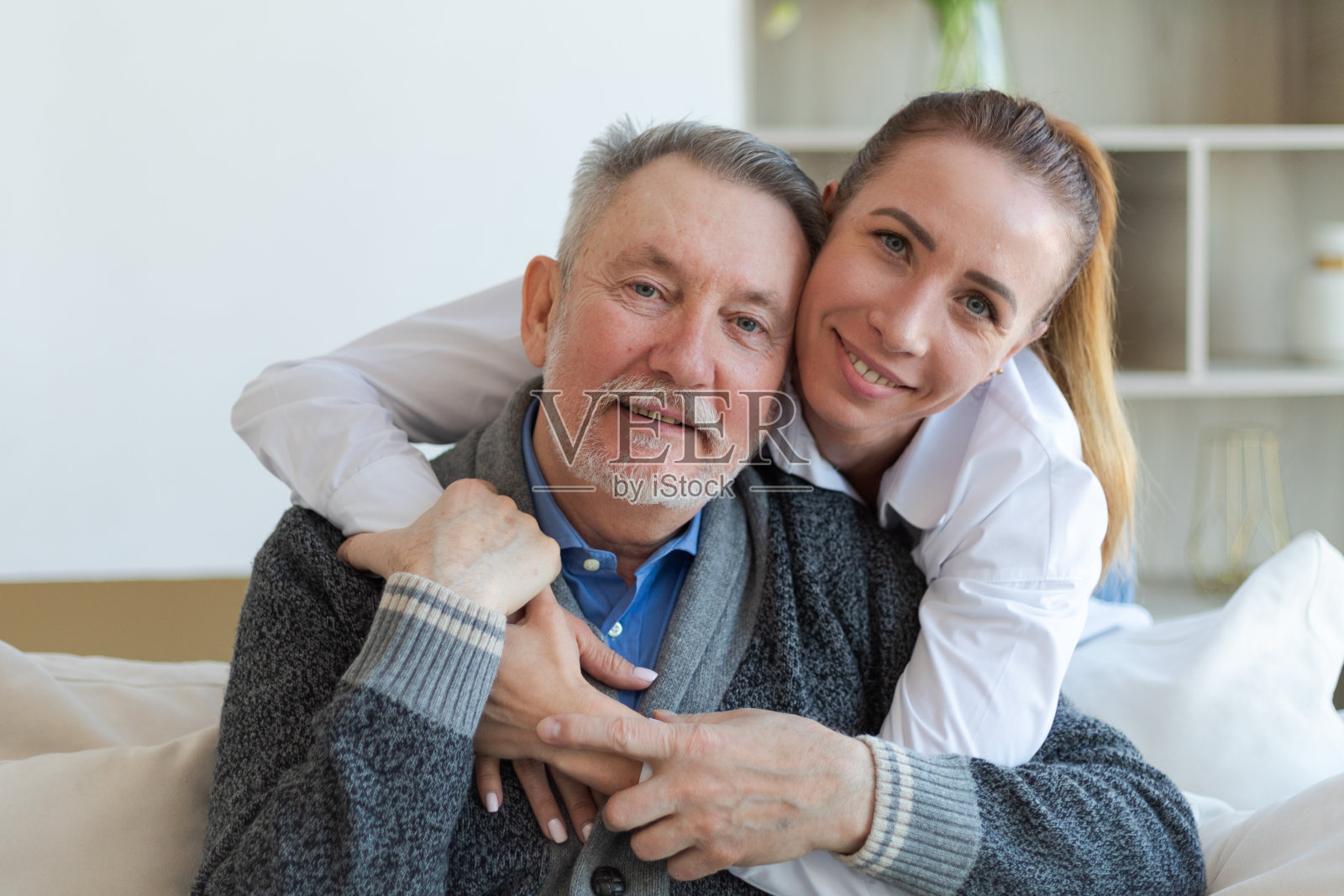 幸福的家庭。有爱心的长大的女儿拥抱慈爱的老人父亲。年轻女子拥抱着爸爸爷爷享受甜蜜的联系。几代人一起待在家里。亲情时刻的爱和关怀。照片摄影图片