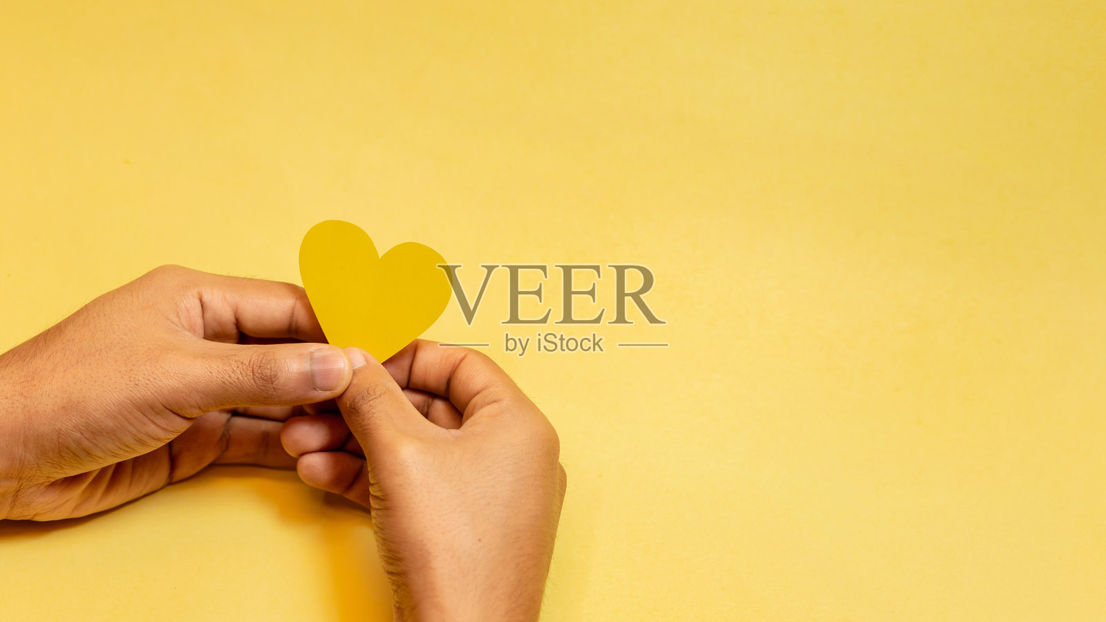 横幅上的手在前景中拿着微笑和黄色的心纸。空格为文字，黄色背景，概念一年中最快乐的一天，快乐的黄色天，夏天。照片摄影图片
