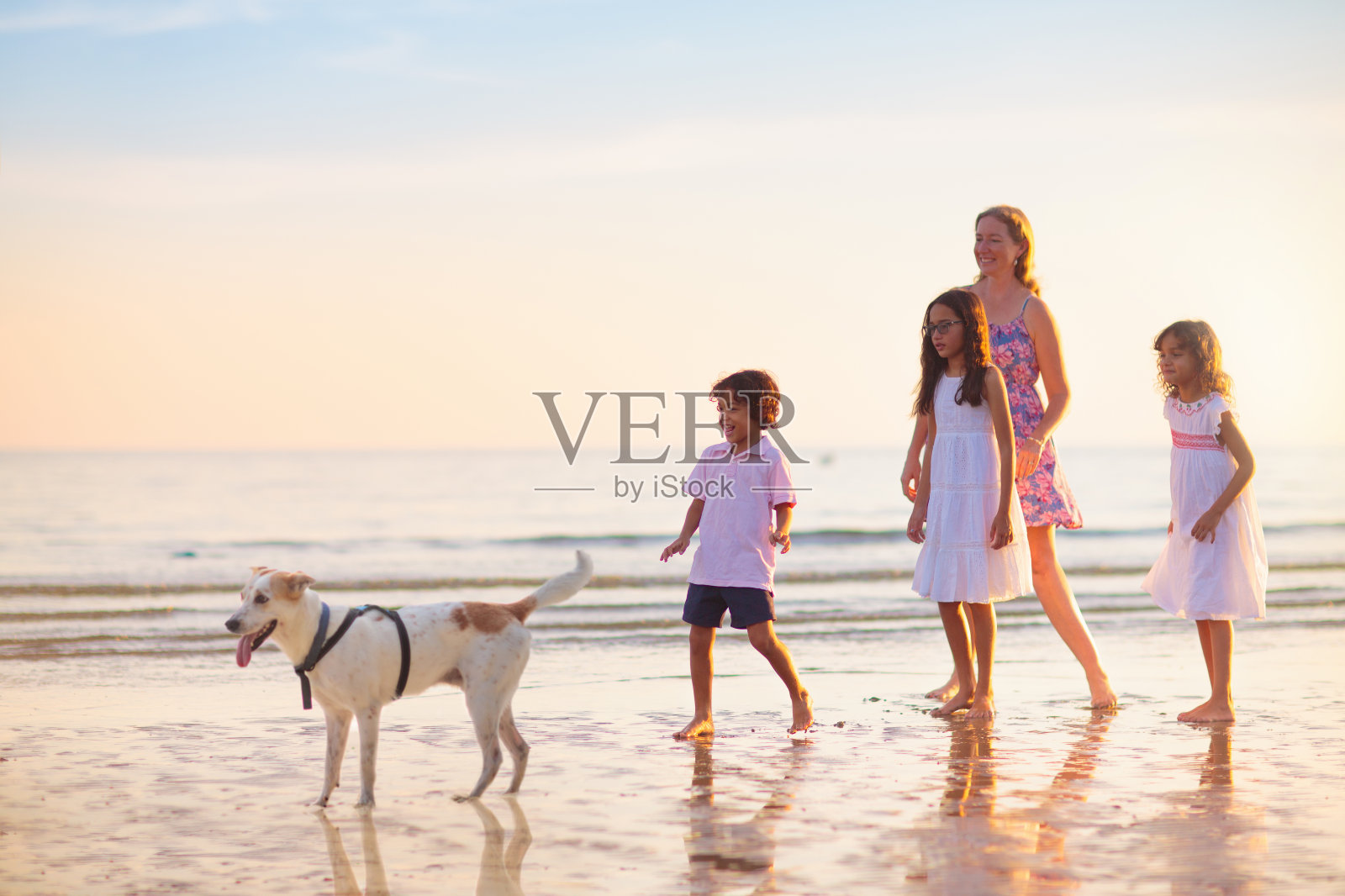 日落时分，一家人在热带海滩上散步照片摄影图片